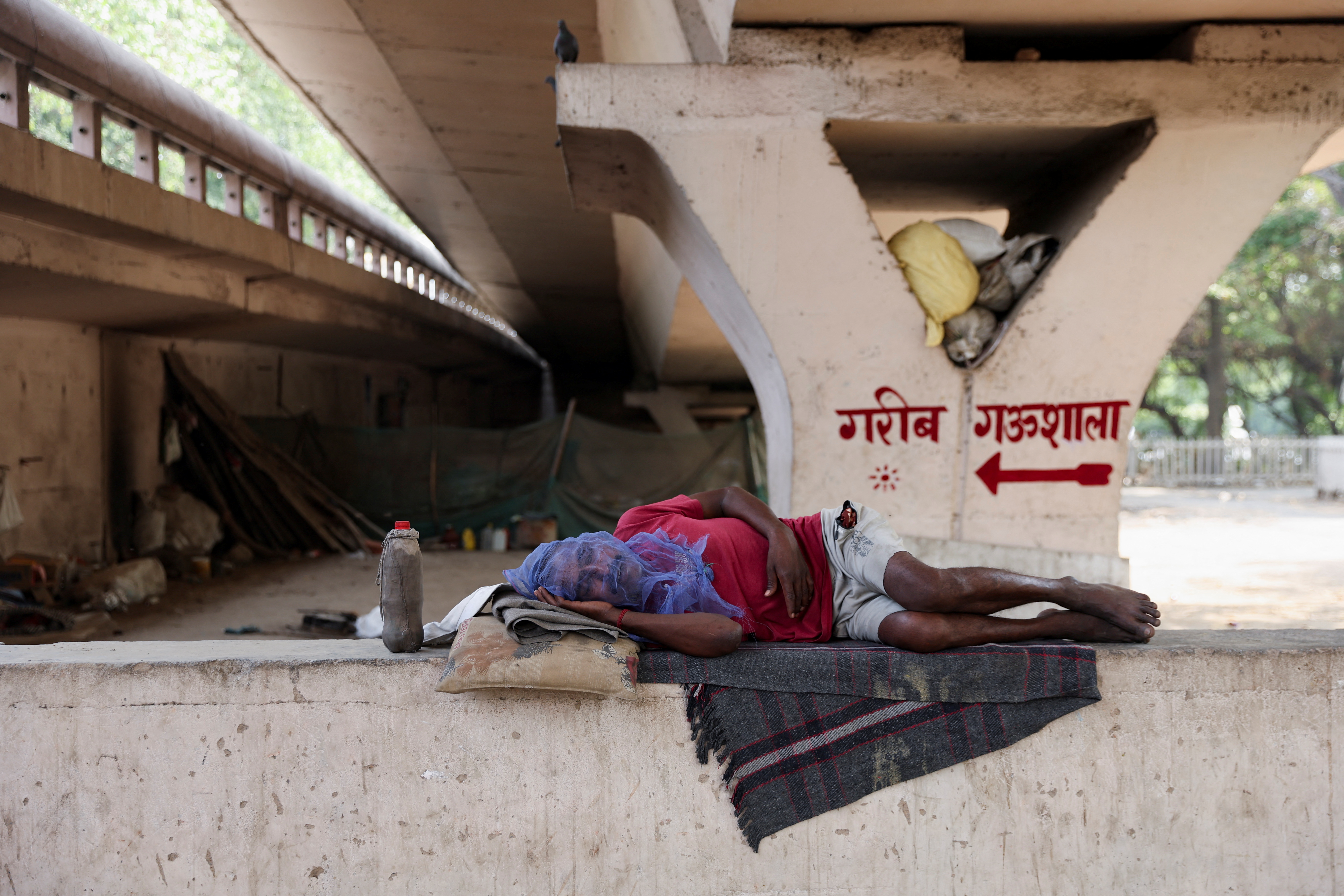 A man sleeps under a bridge on a hot summer day in New Delhi