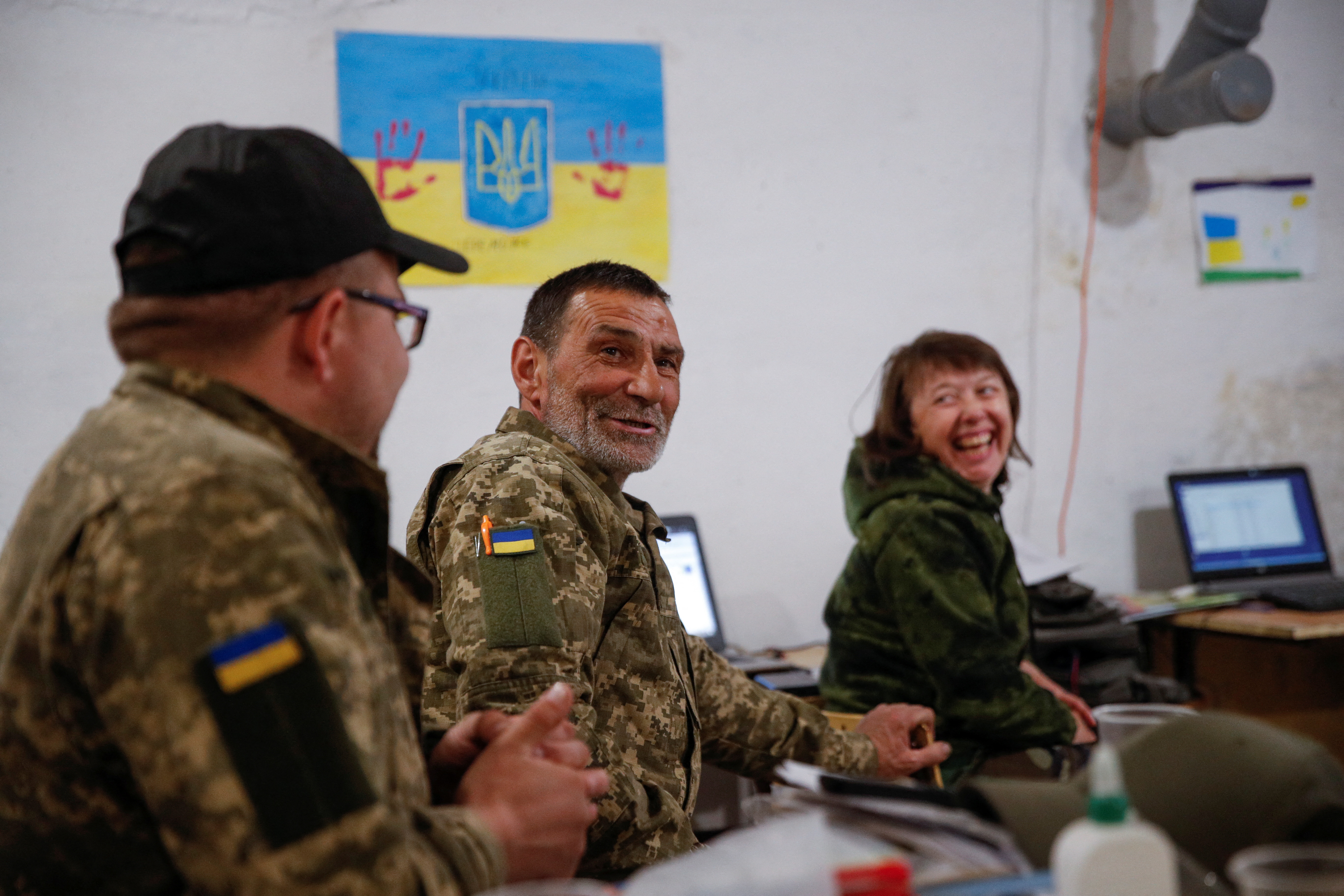 Ukrainian service members watch the performance of Kalush Orchestra during the final of the 2022 Eurovision Song Contest on May 14, 2022 [Valentyn Ogirenko/Reuters]