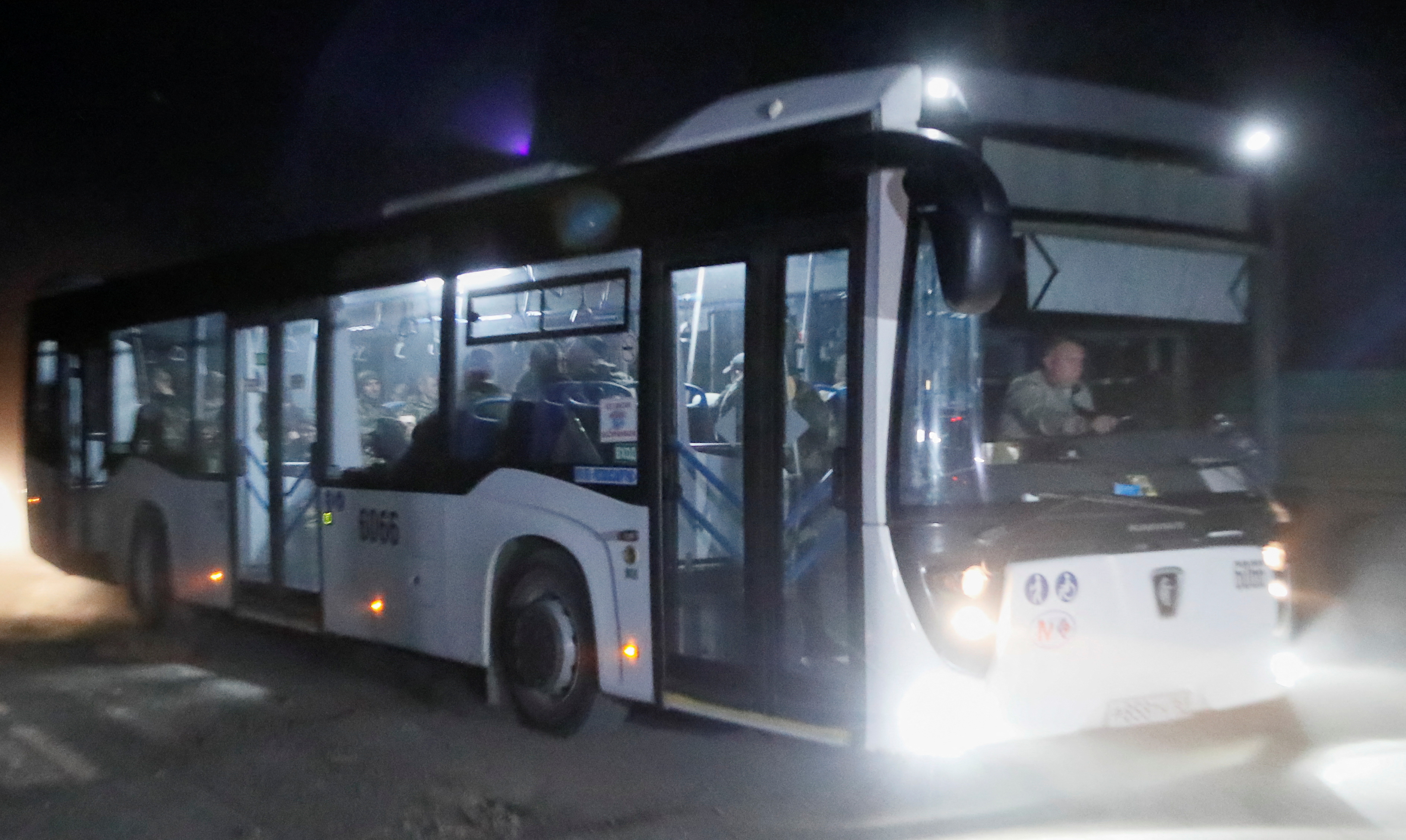 A bus carrying service members of Ukrainian forces from the besieged Azovstal steel mill drives away under escort of the pro-Russian military in Mariupol, May 16