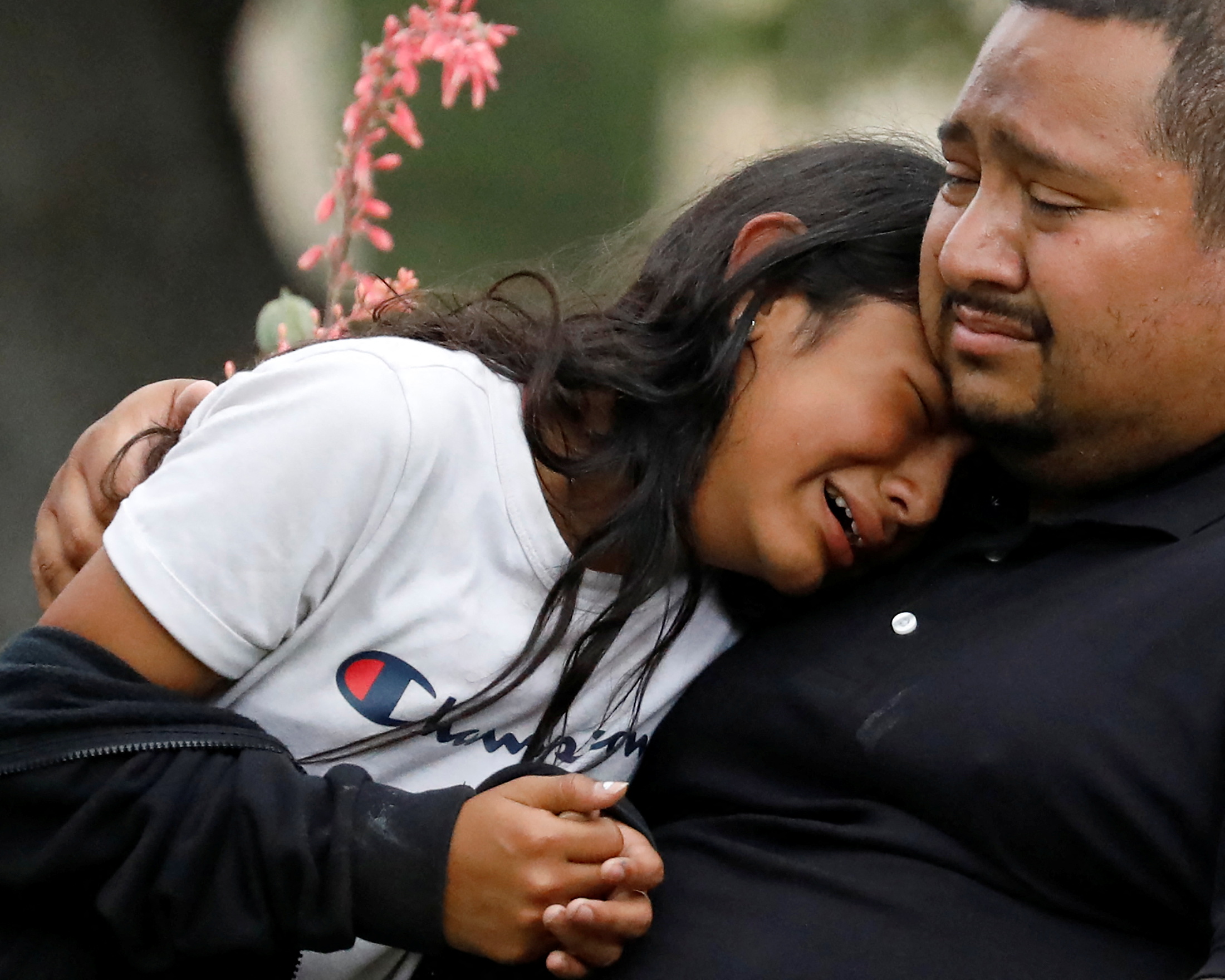 A young woman cries on the shoulder of a man.