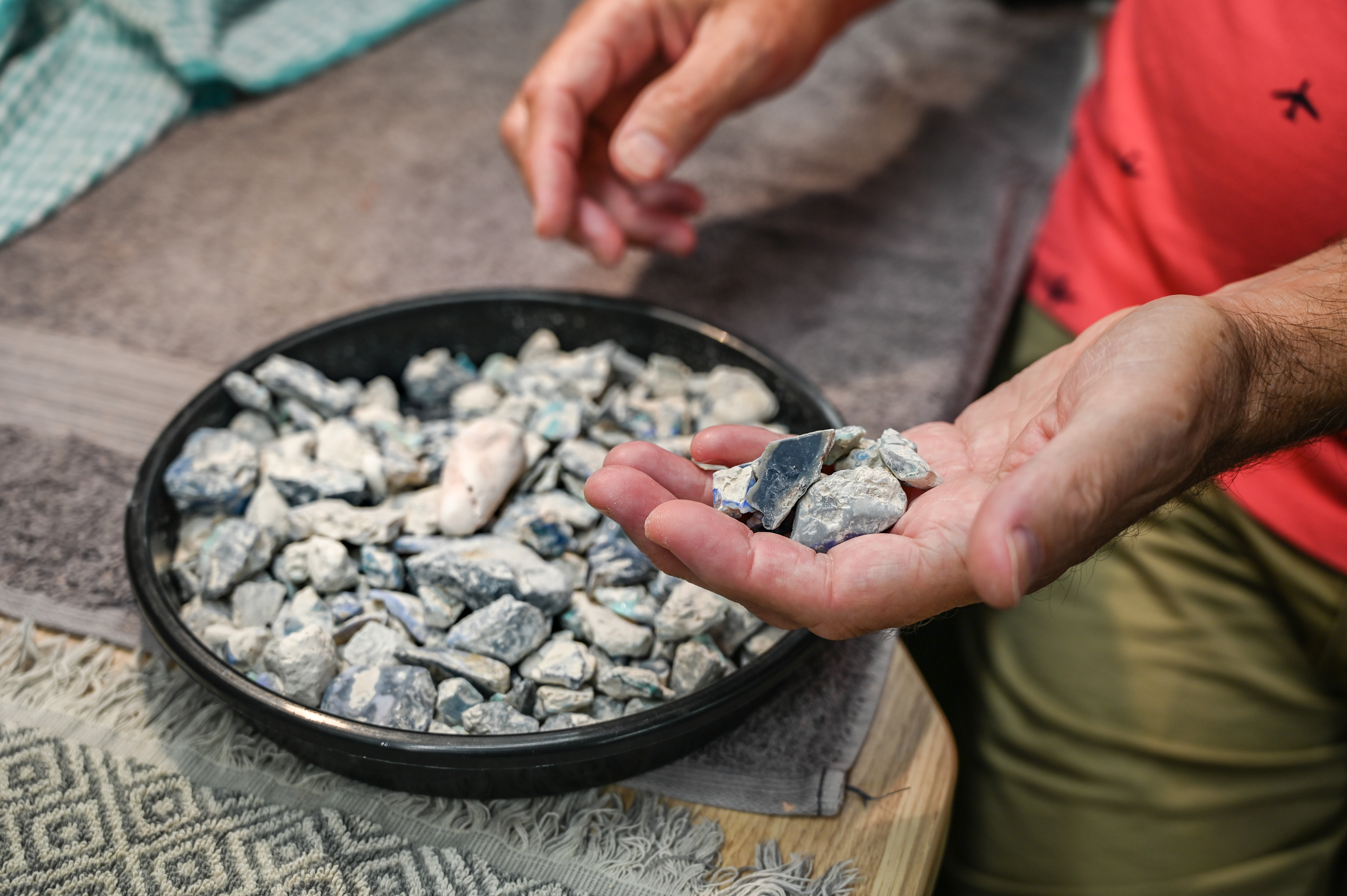 A photo of Andrew holding a handful of rough opal stone.