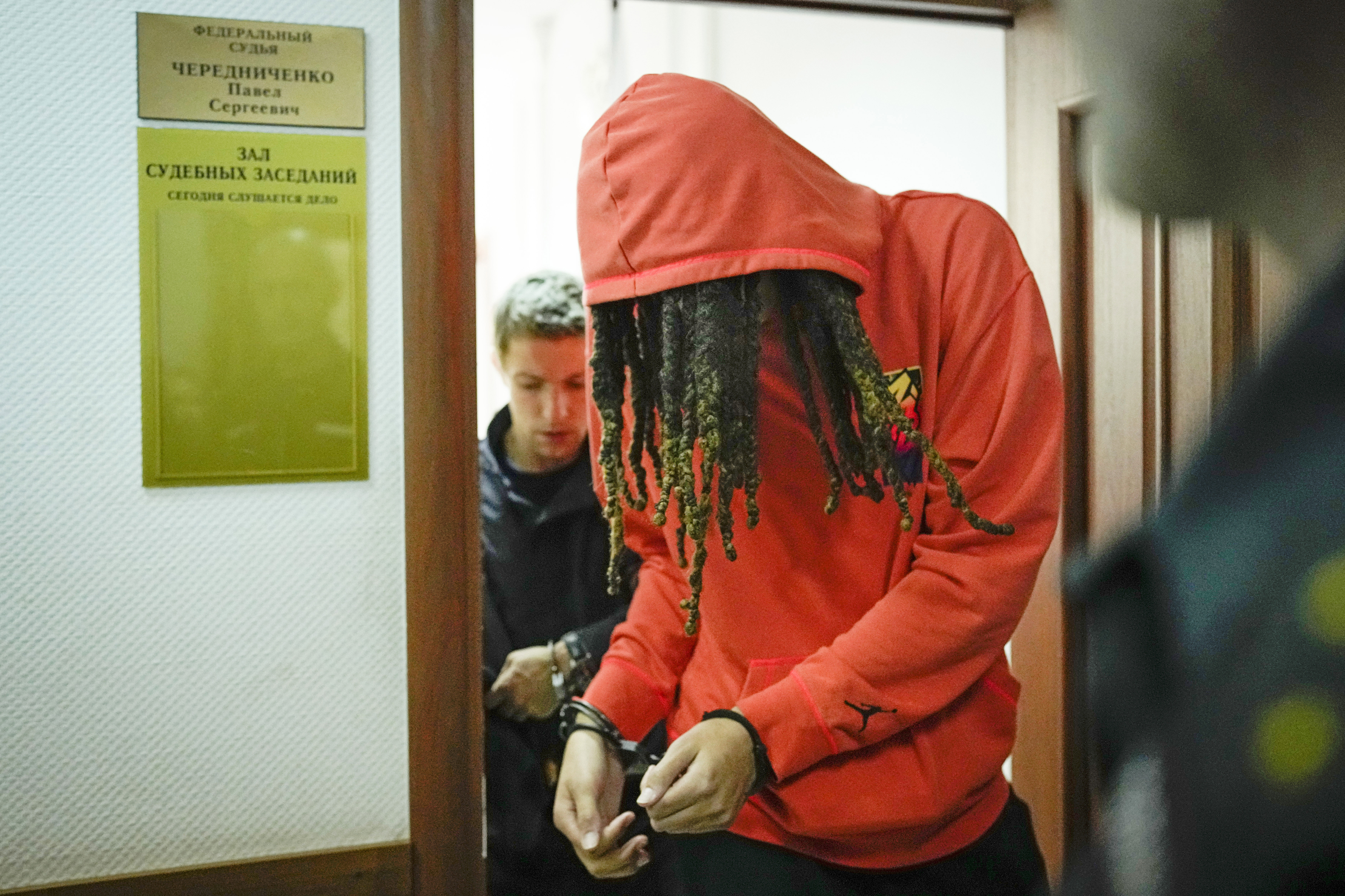 WNBA star Brittney Griner attends a court hearing in Moscow in handcuffs and with a red hoodie over her head