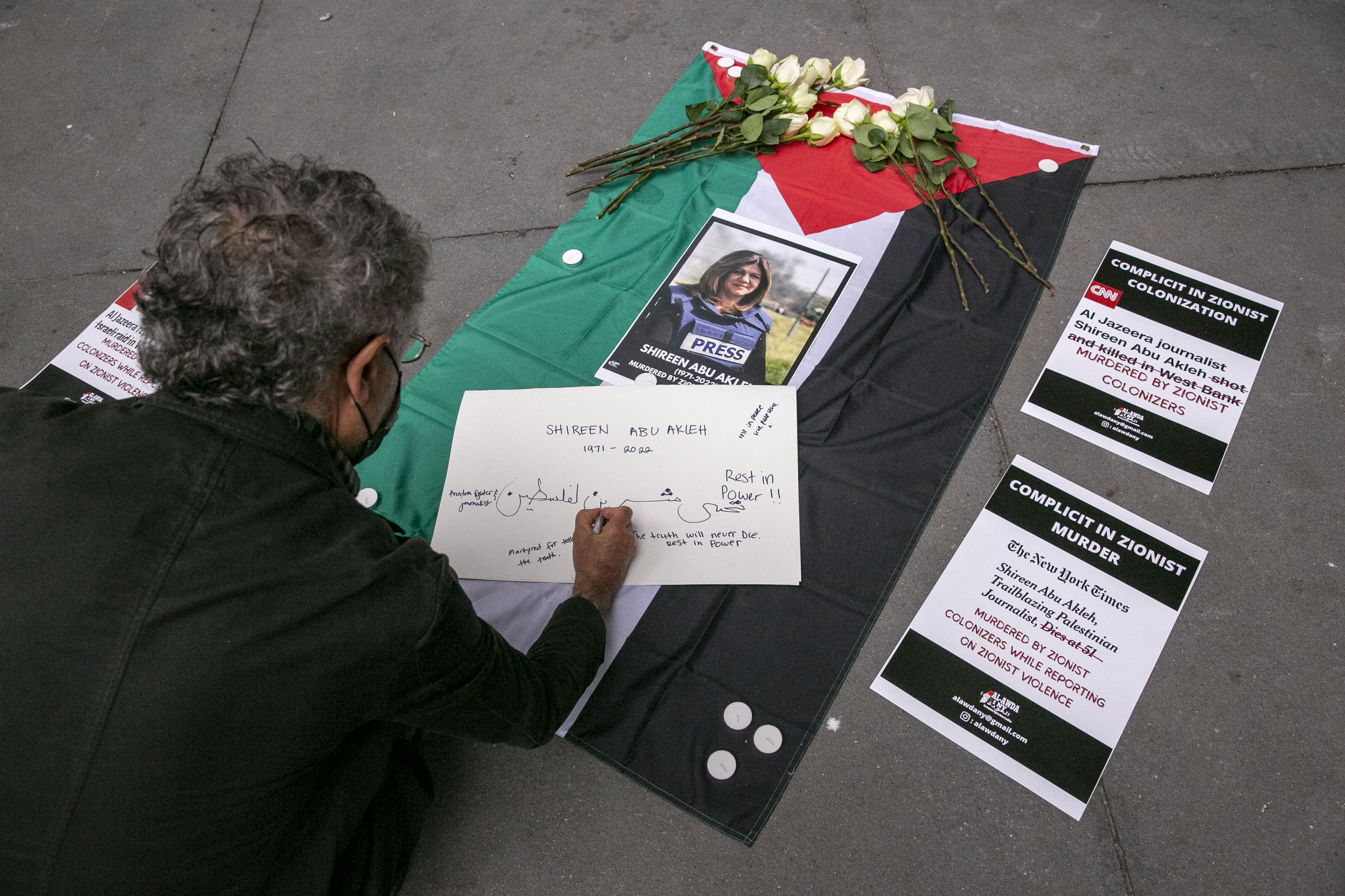 A man writes a message for the Palestinian-American journalist Shireen Abu Akleh during a memorial and rally in her honour outside The New York Times office building, in New York, US, 13 May 2022.