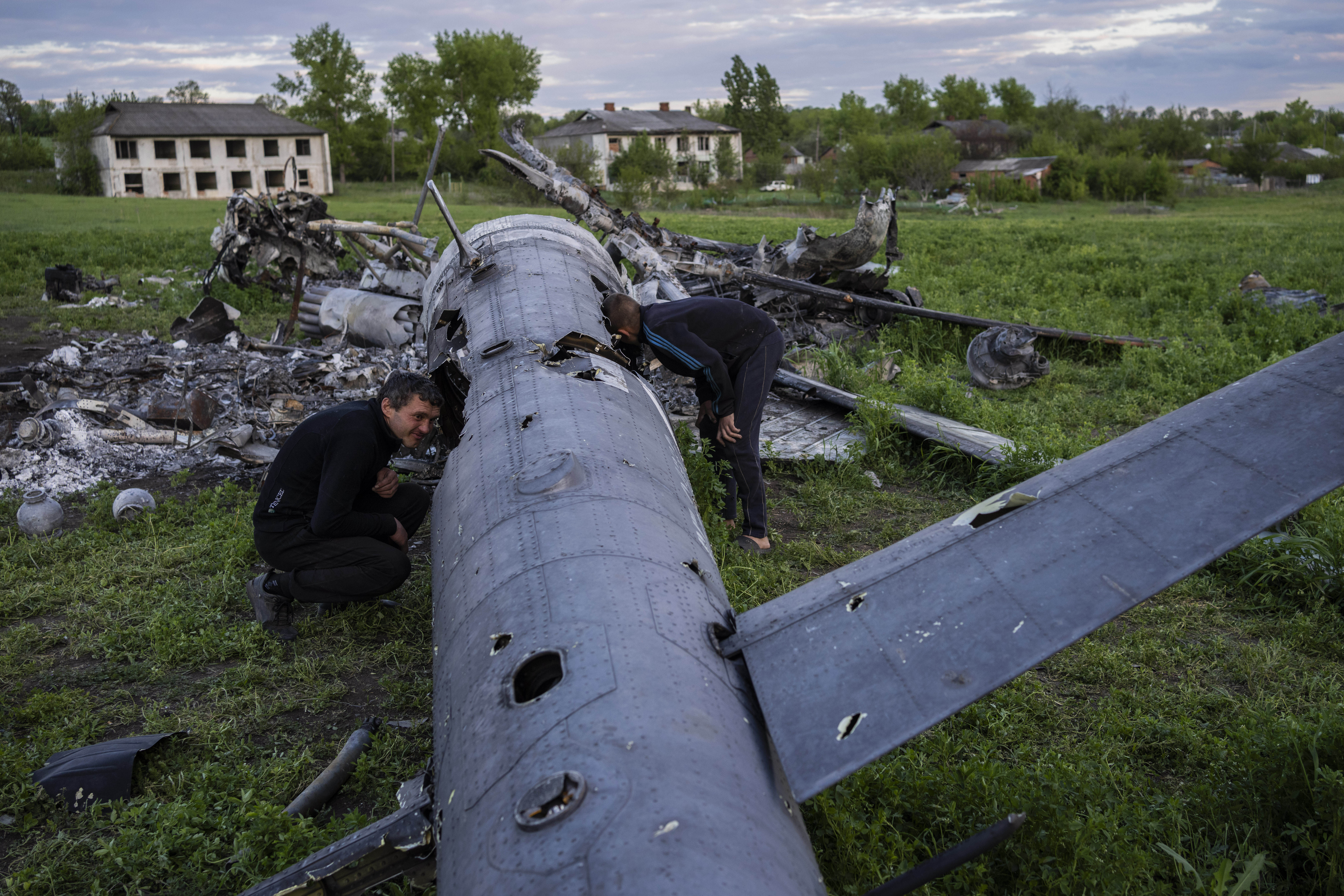 Oleksiy Polyakov, right, and Roman Voitko, check the remains of a destroyed Russian helicopter in a field in the village of Malaya Rohan, Kharkiv, Ukraine, May 16