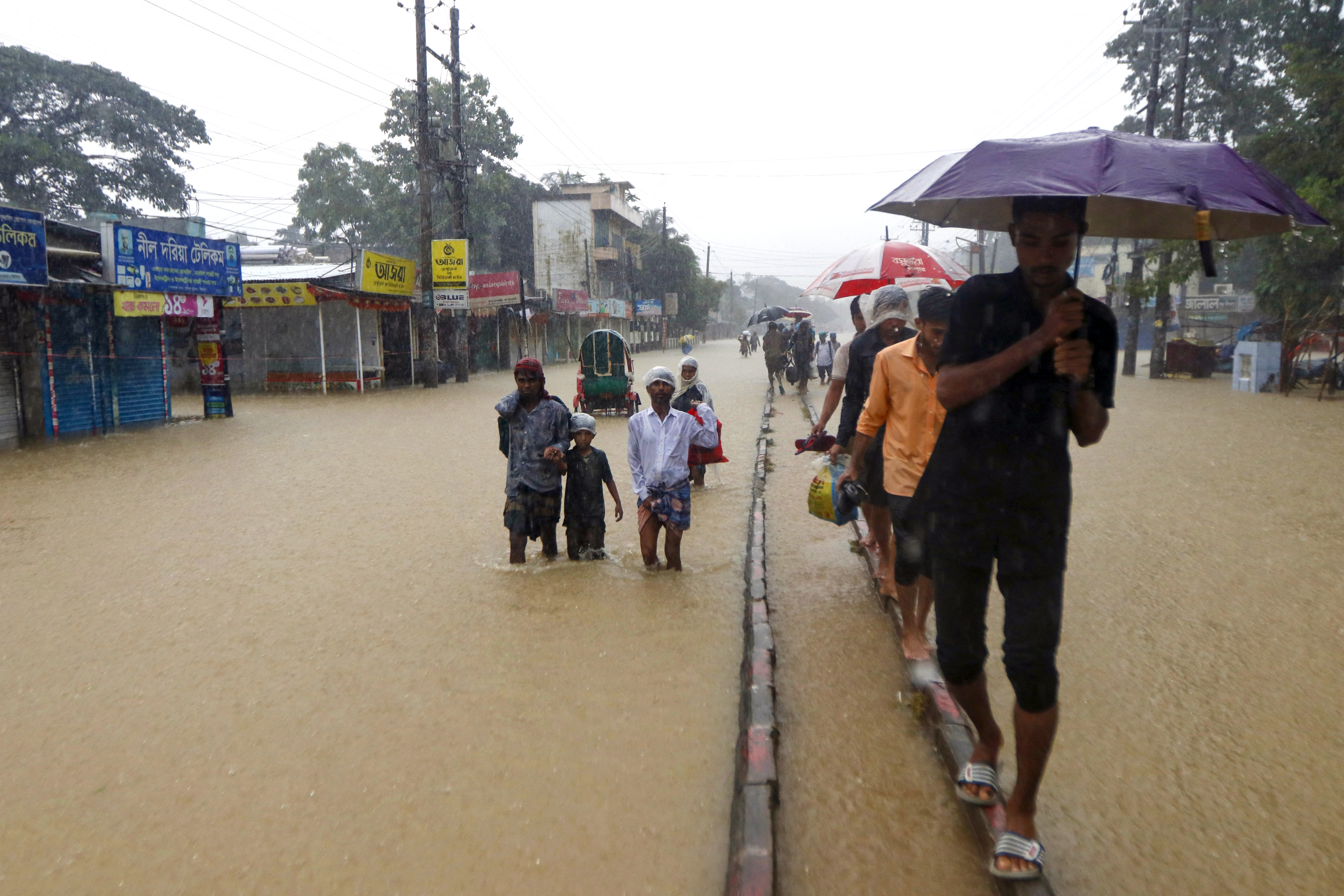 People wade along a road in a flooded area