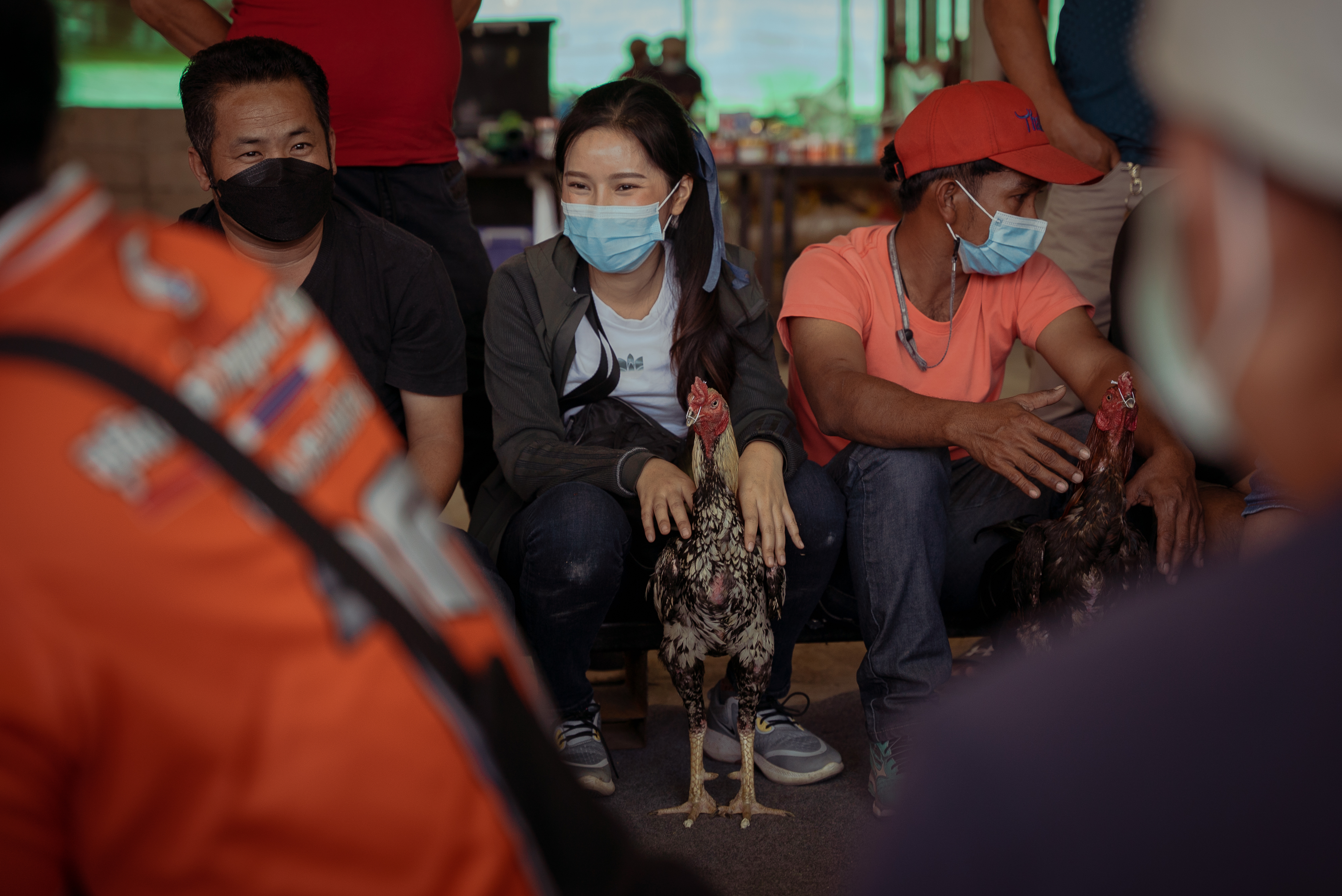Mod sits among the other cockerel owners as they wait to pair their birds for a fight. It is rare to see women in cockfighting
