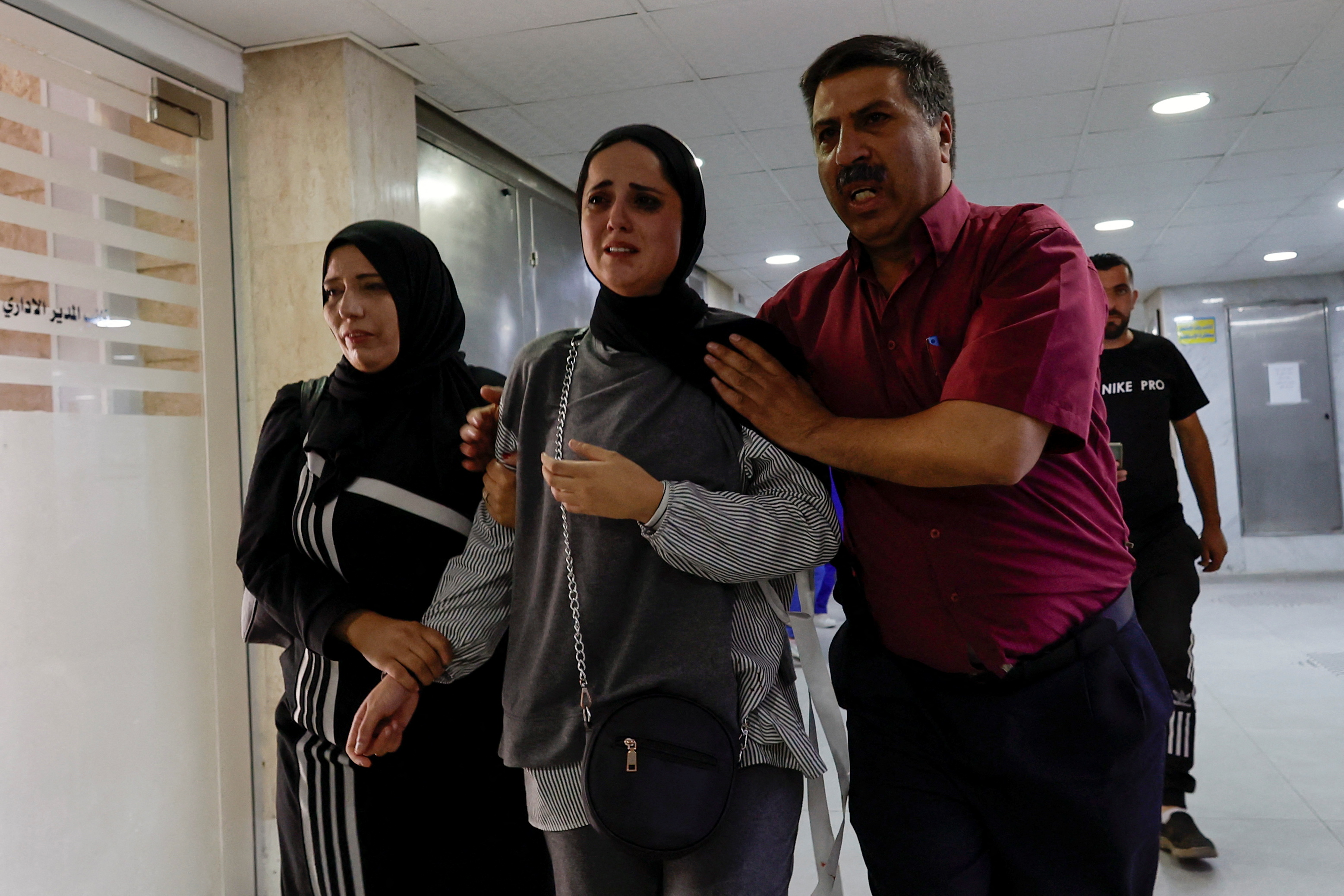 Two women and a man console each other in a hospital.