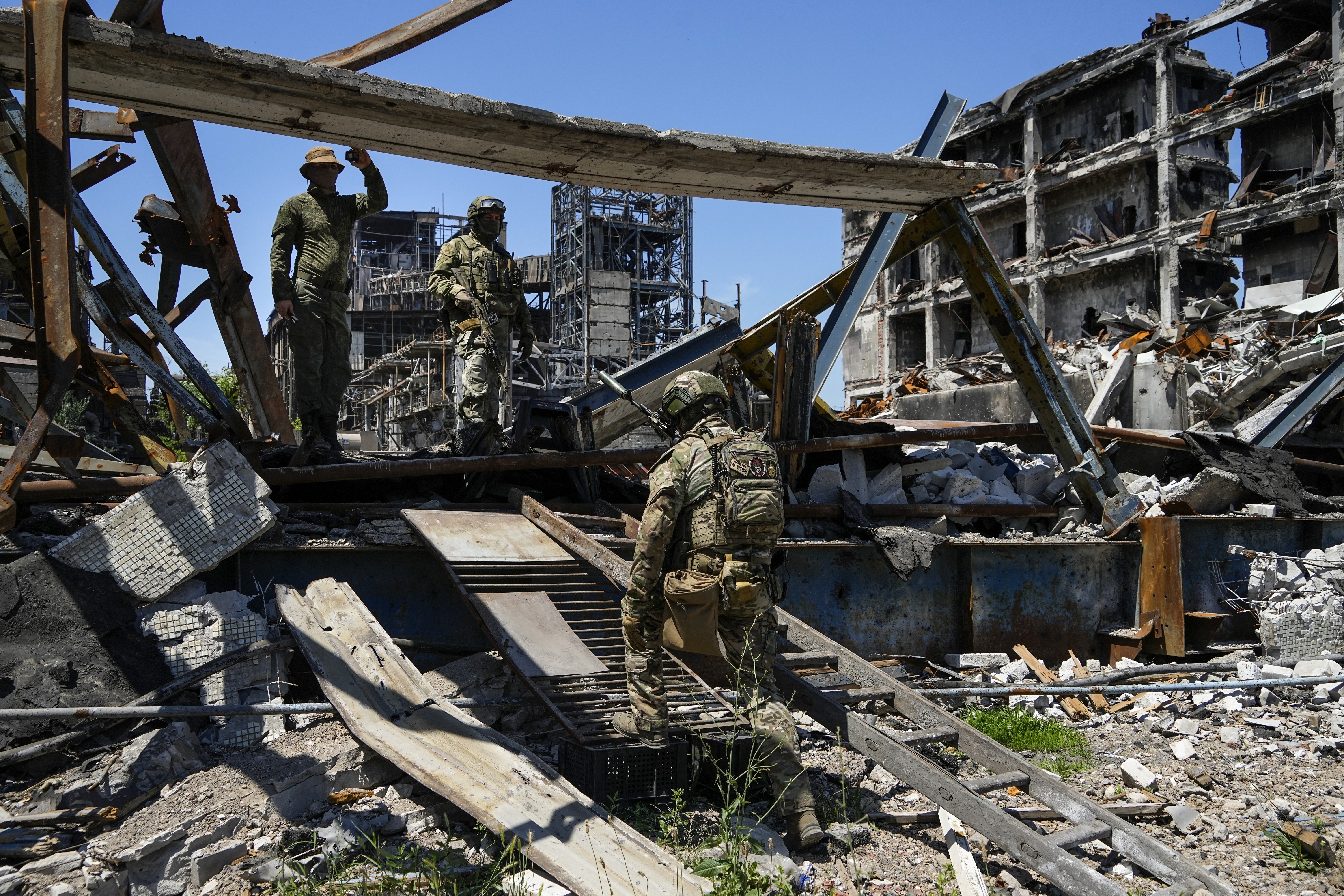 Russian soldiers walk through debris