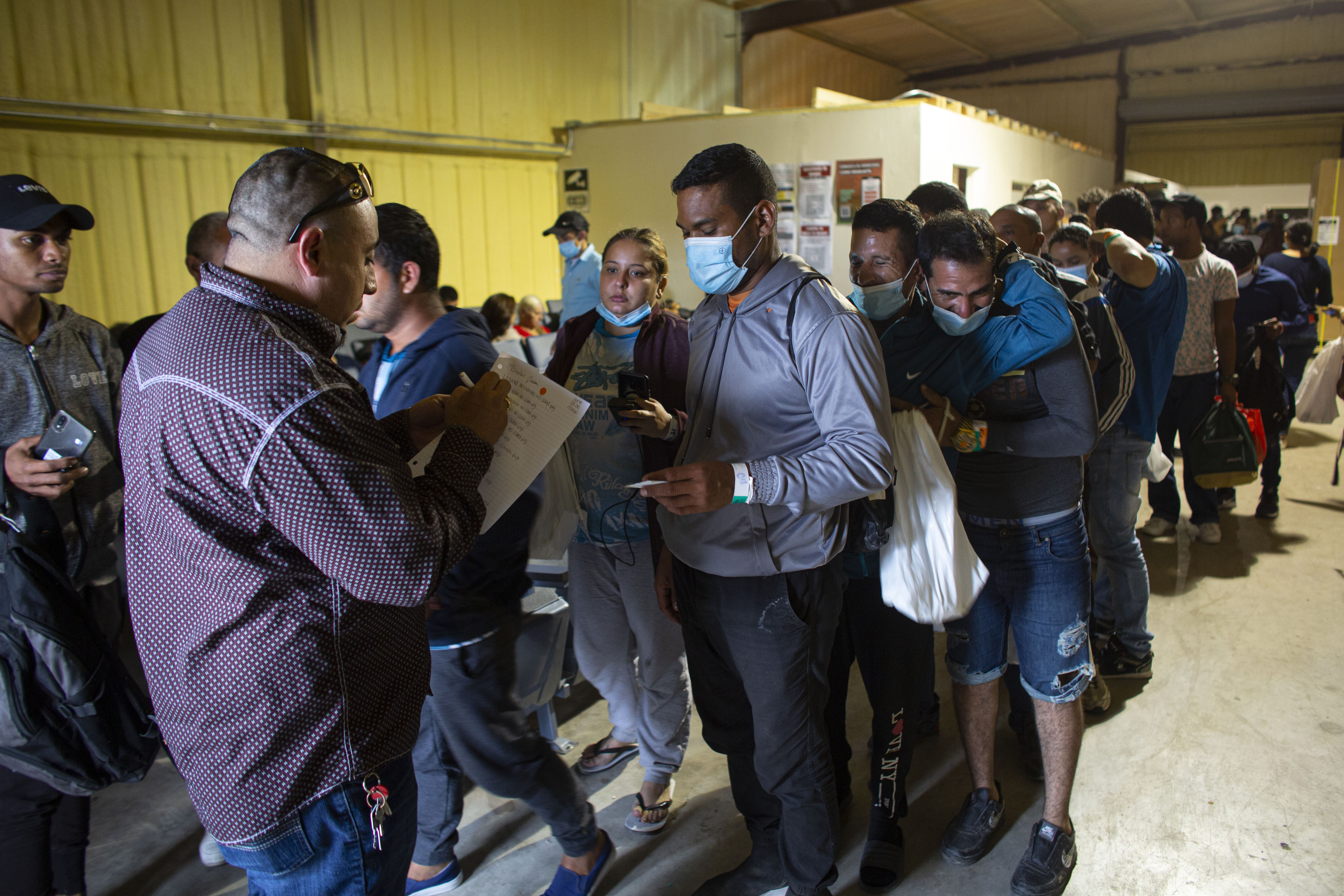 Migrants queue for a commercial bus that will take them to the San Antonio airport, in Eagle Pass, Texas
