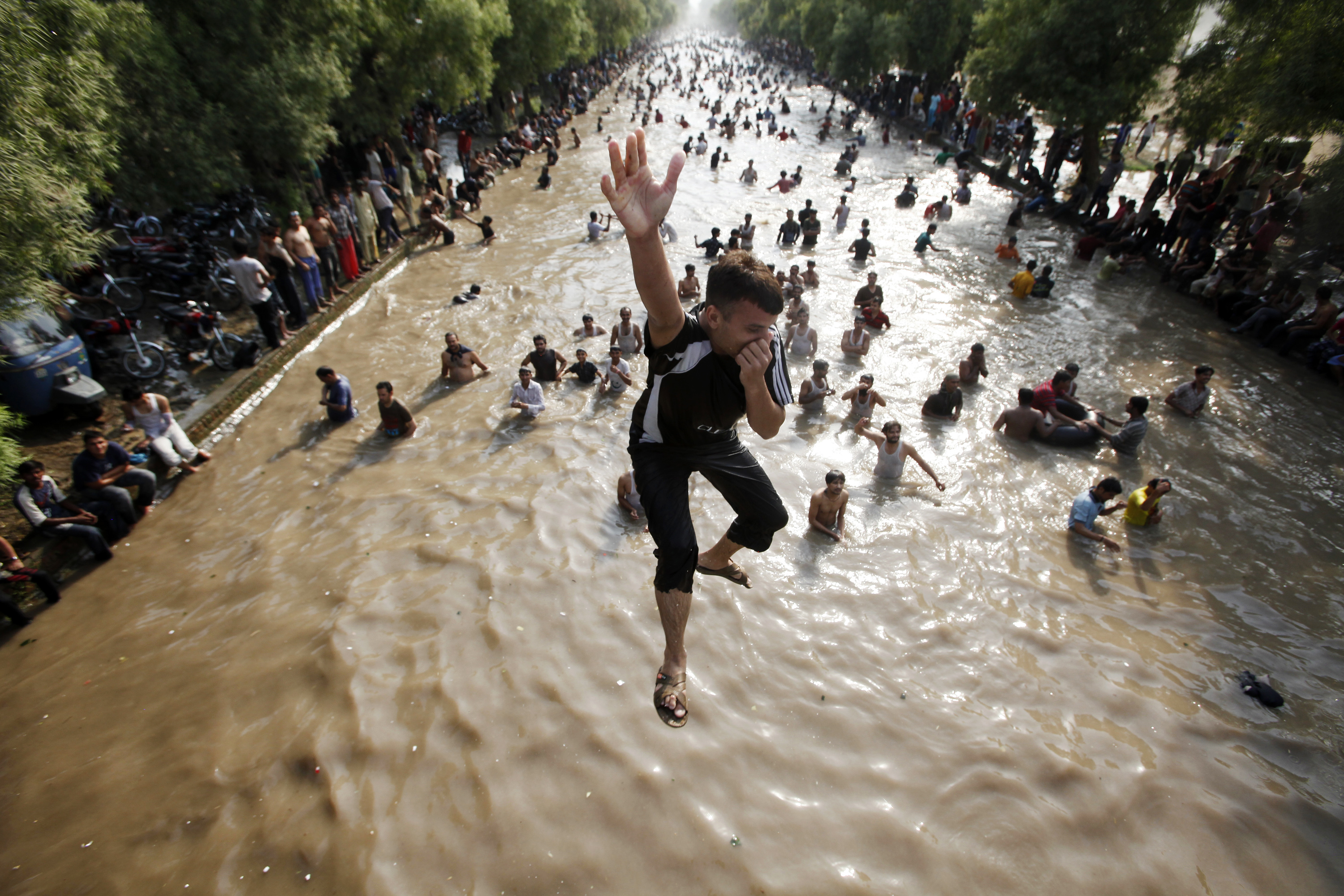 A boy jumps into a canal to cool himself on a sweltering hot day in the eastern city of Lahore, Pakistan [File: Mohsin Raza/Reuters]
