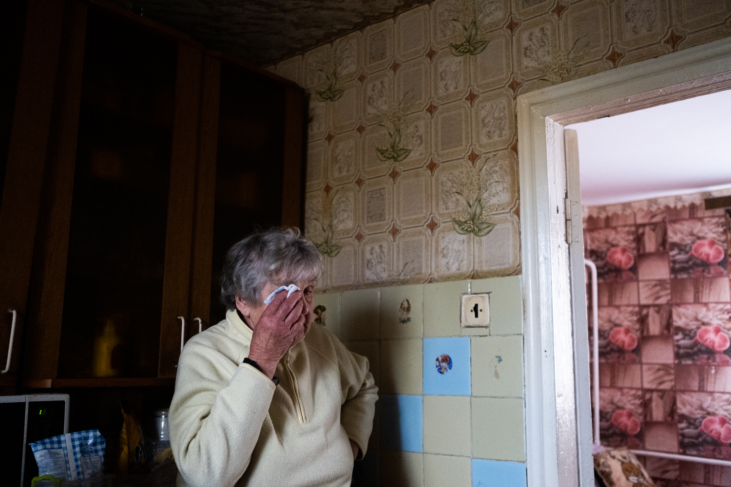 A woman wipes away her tears in a room.
