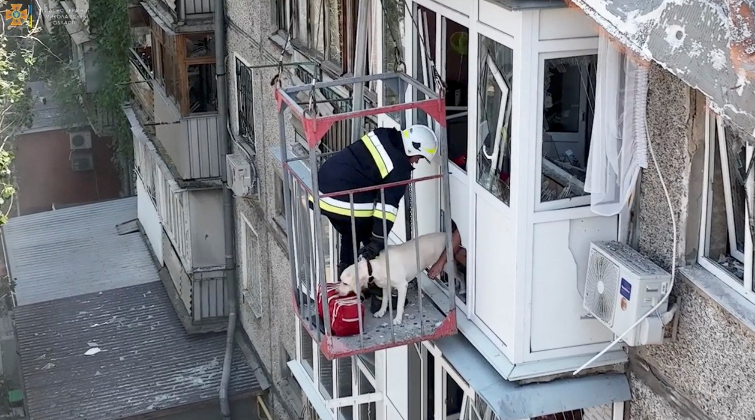 Rescuers evacuate a dog from a damaged residential building following a missile attack in Mykolaiv, Ukraine, June 29, 2022