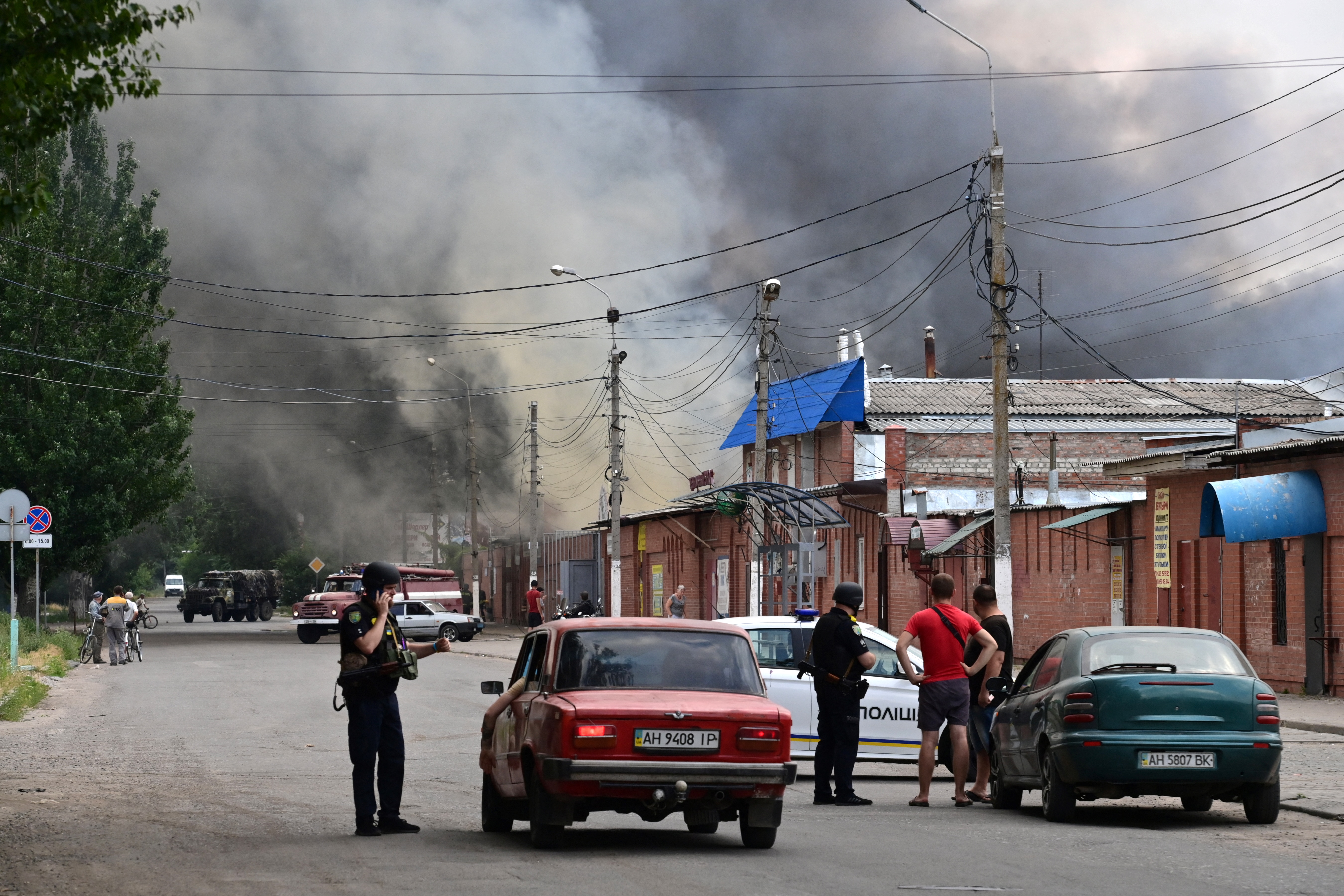 Security personnel halt motorists as smoke rises from the central market of Sloviansk, north of Kramatosk on July 5, 2022