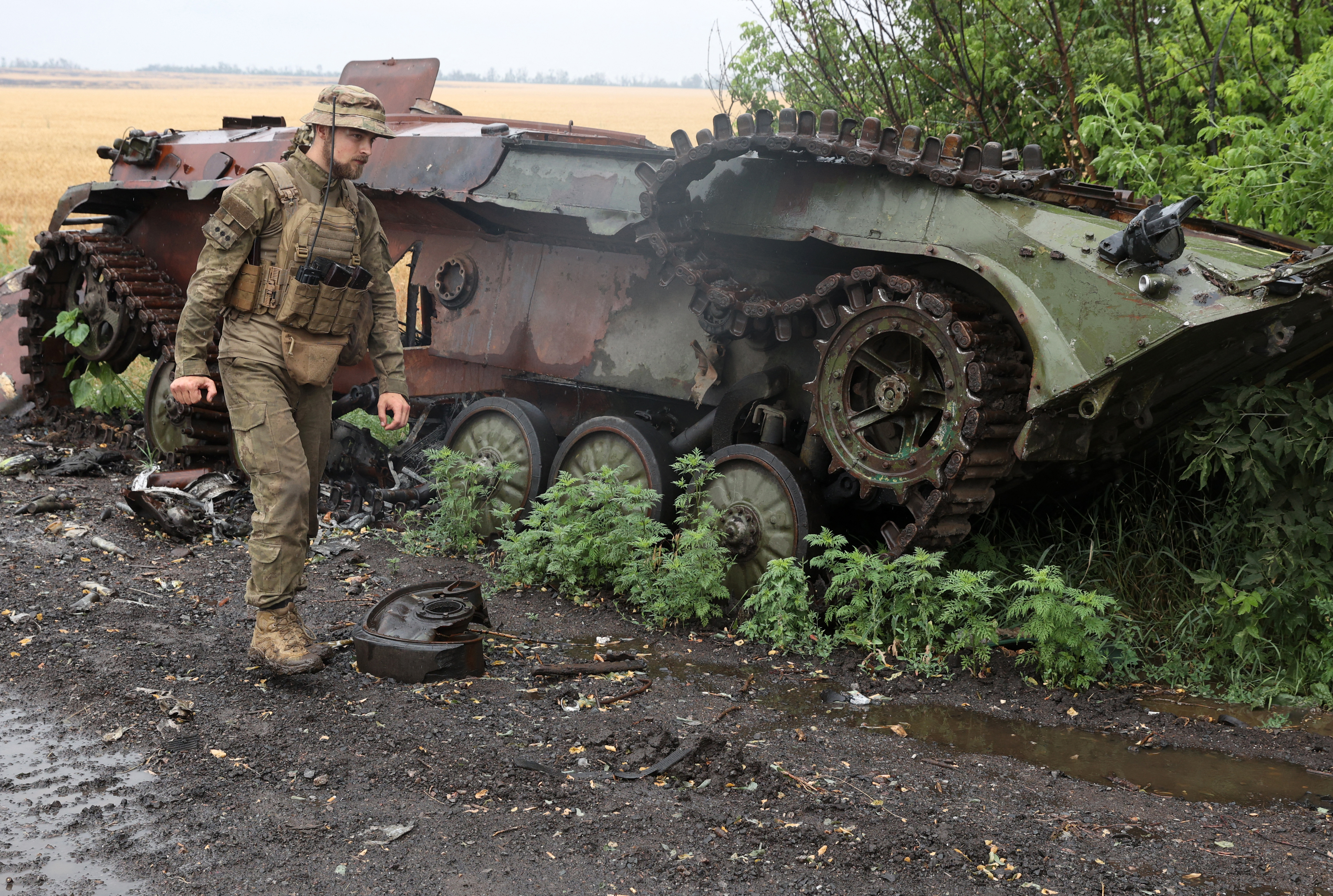 Ukrainian serviceman walks past a destroyed armoured personnel carrier near the front line in the south of Kharkiv region