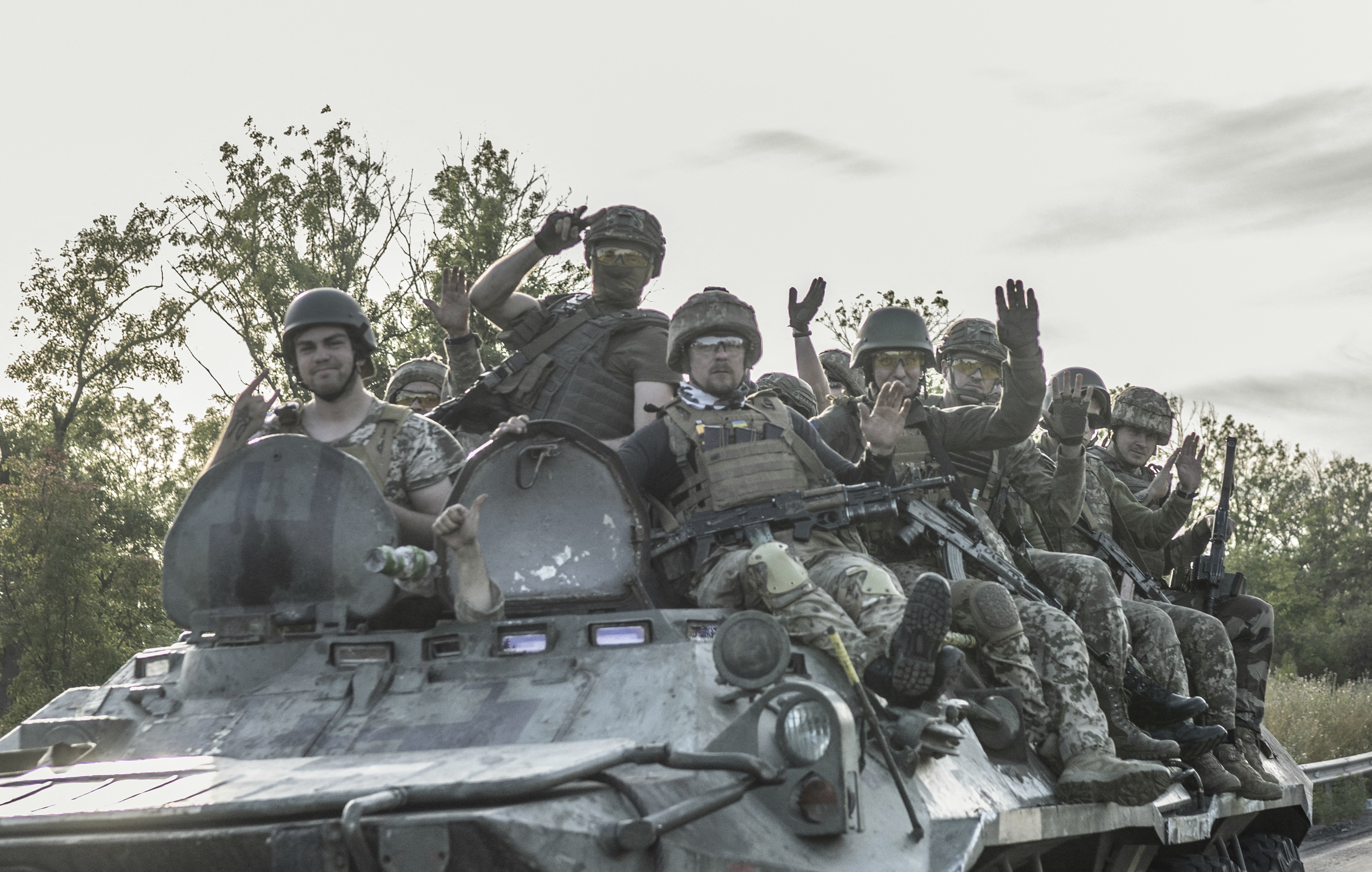 Ukranian soldiers sit a top of an armoured vehicle as it drives to frontline on the outskirts of Bakhmut