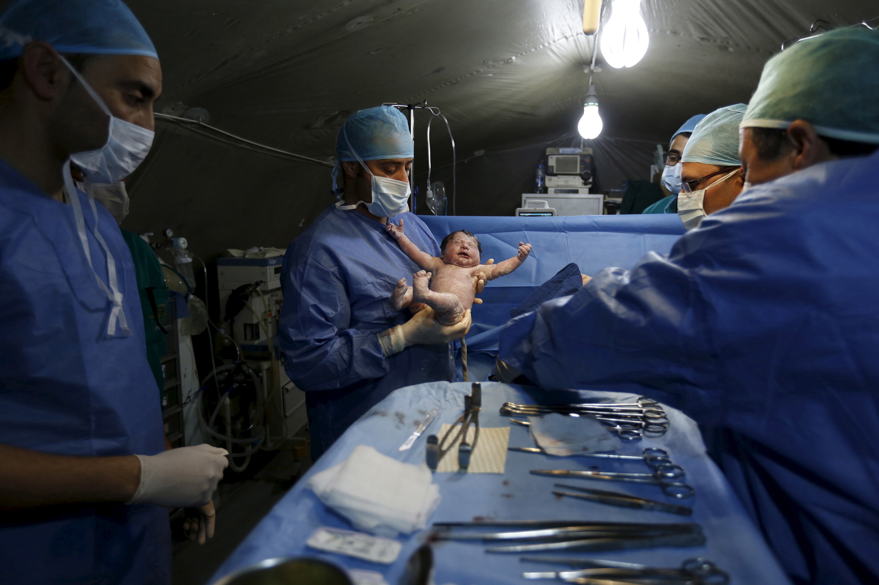 Moroccan doctors carry a Syrian baby Siwar, who was born by Caesarean section in a field hospital in Zaatari refugee camp, March 7, 2016