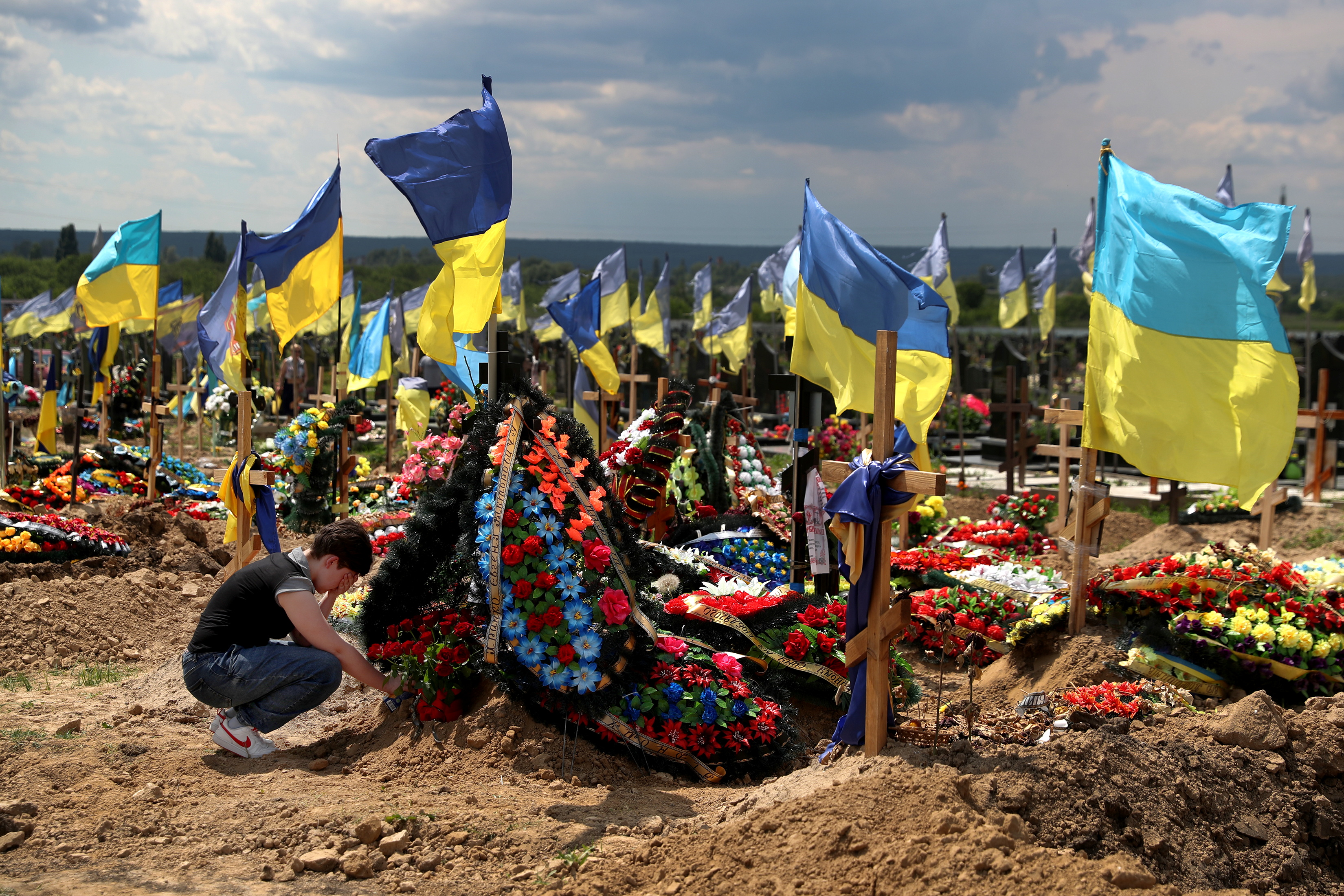 A woman reacts next to a grave of Evgeny Khrapko, a combat medic and instructor of tactical medicine who was killed in a mission, amid Russia's attack on Ukraine, after his farewell ceremony in Kharkiv, Ukraine June 14, 2022. REUTERS/Ivan Alvarado