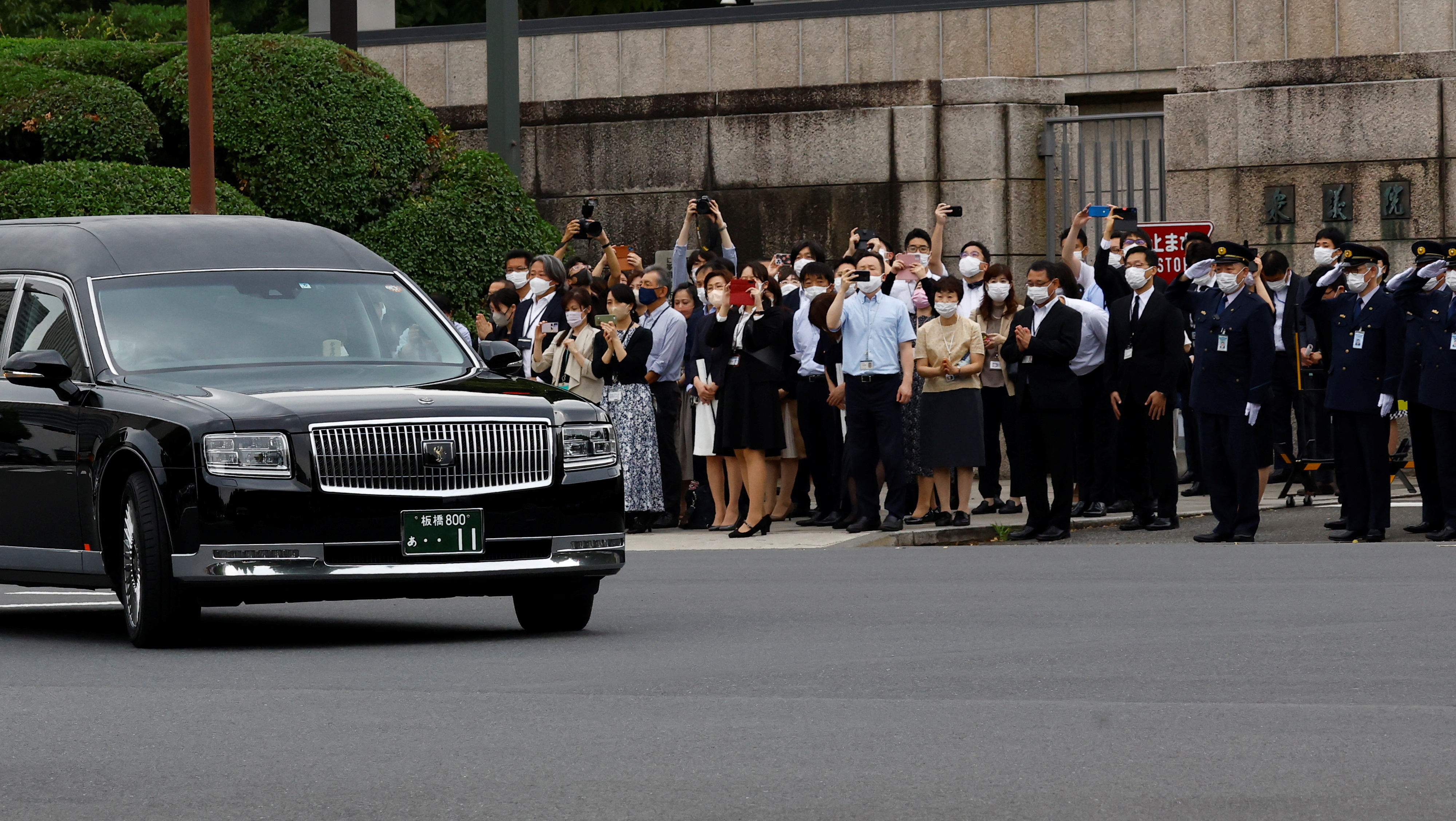 Guards stand to attention as people watch the hearse carrying Abe’s body in front of the Japanese parliament following his funeral in Tokyo