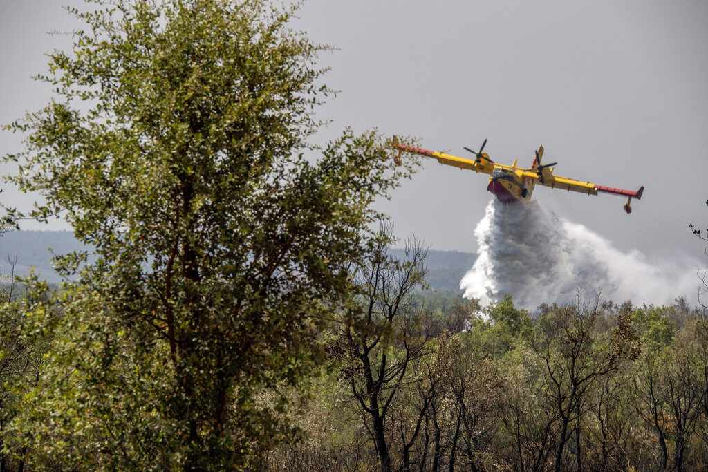 Fire-fighting planes drop water to put out a forest blaze in Laarach [AP Photo]