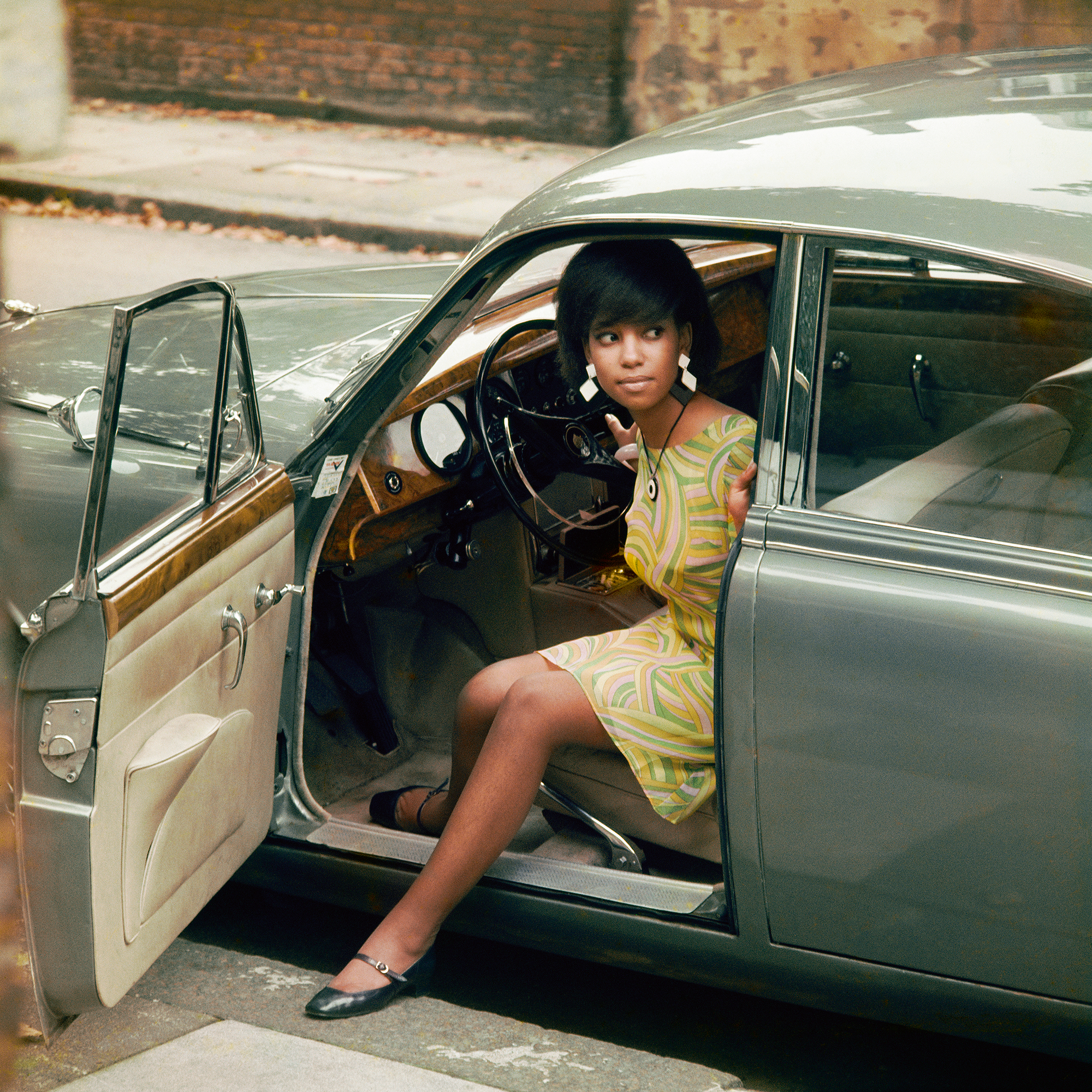 Erlin Ibreck stepping out of a Jaguar in Kilburn, London, 1966