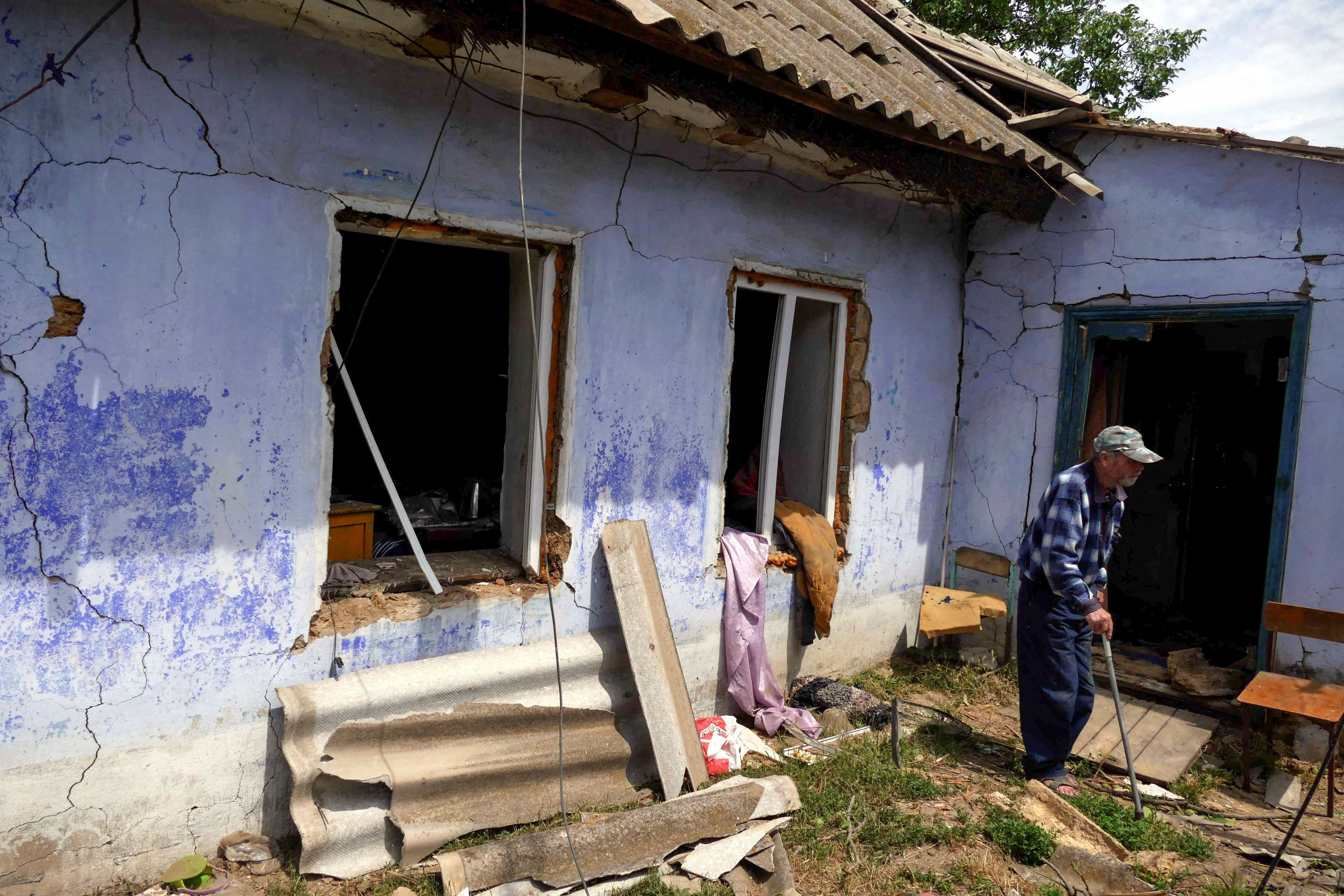 A local resident stands beside a house damaged by a Russian missile in the village of Maiaky, in Odesa region, Ukraine on June 27, 2022