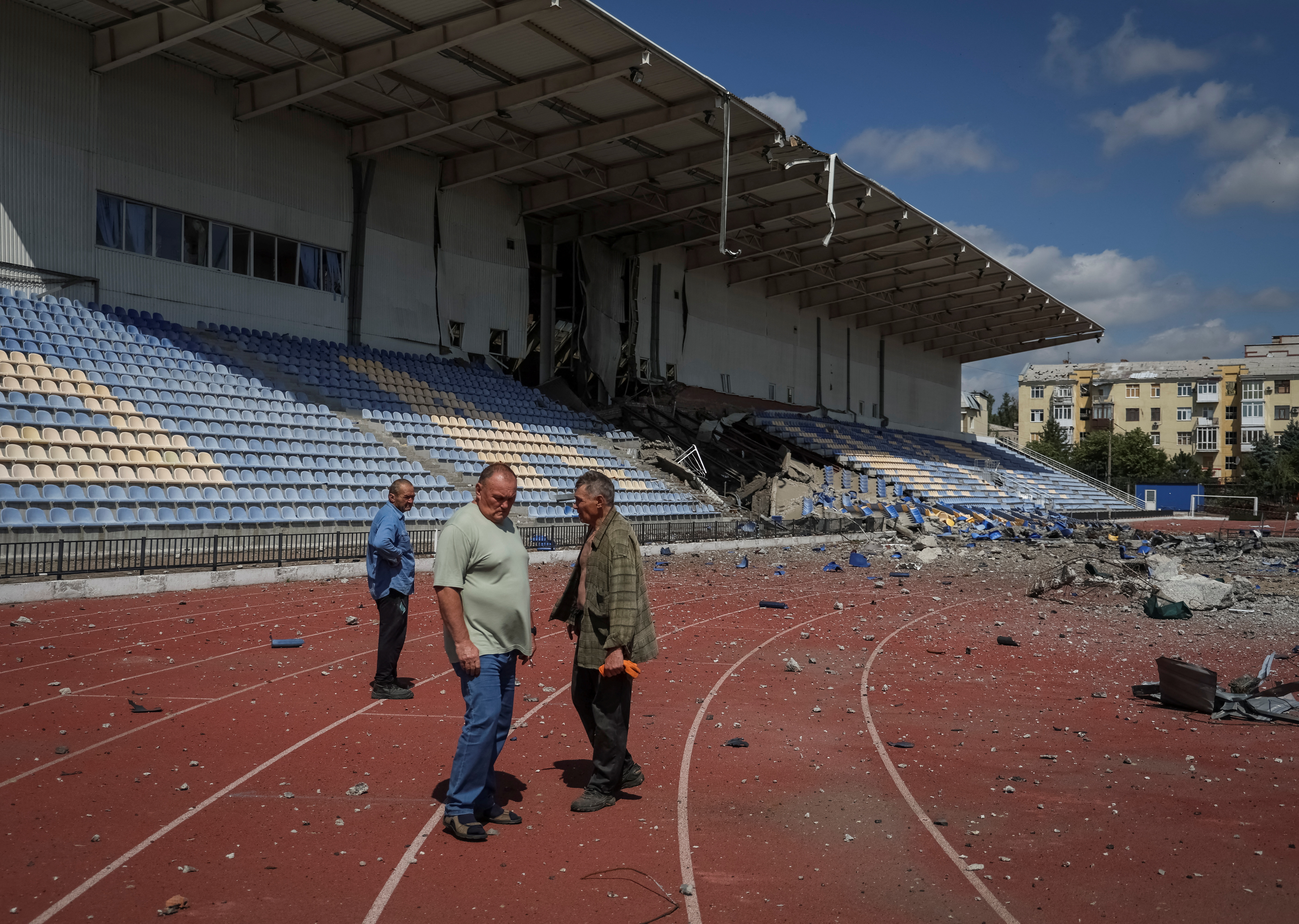 Employees stand at a stadium damaged by a Russian military attack in Bakhmut, Ukraine, July 12, 2022