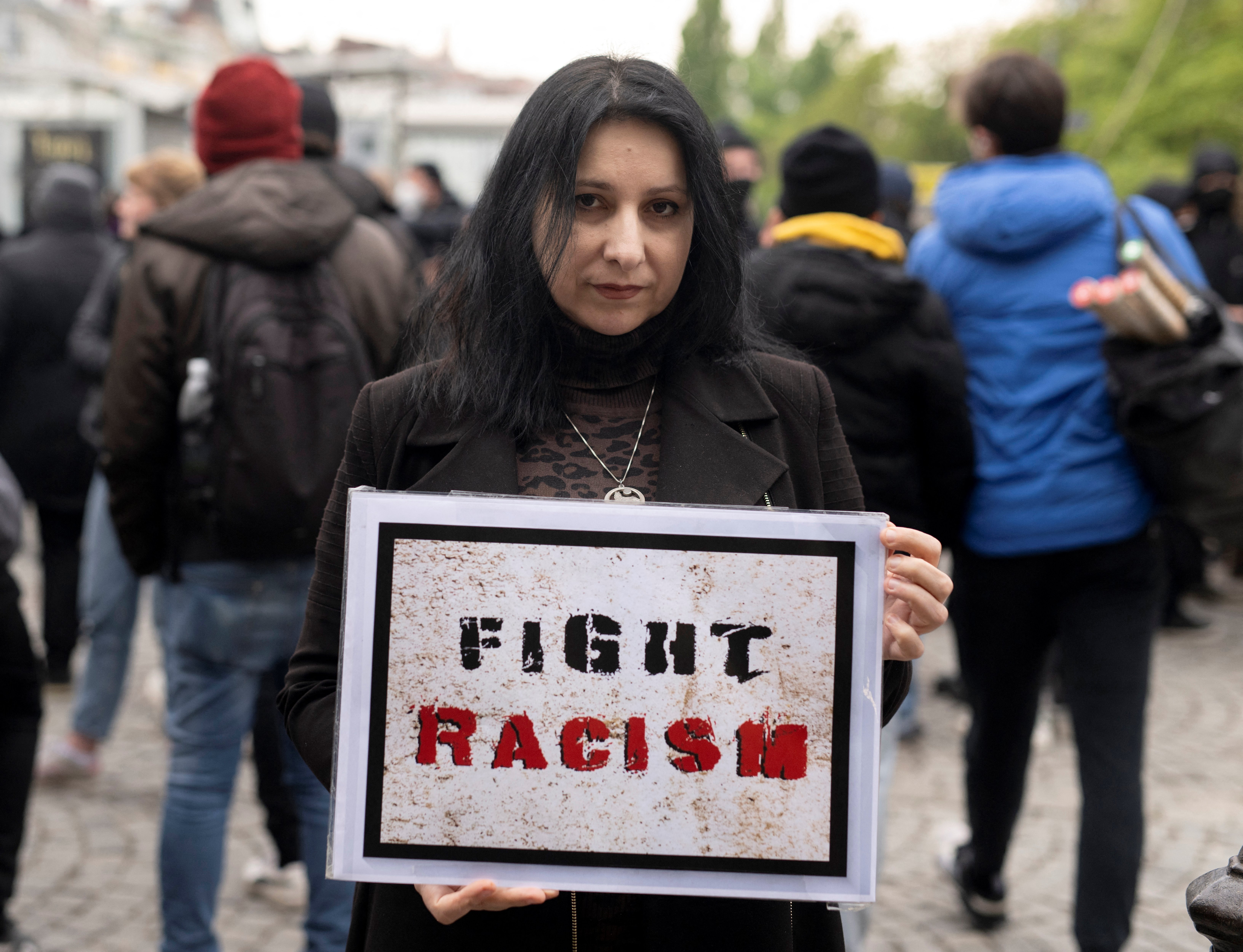 Chechen activist Rosa Dunaeva poses for a photo with a poster reading 'Fight Racism' in Vienna, Austria on April 27, 2022. - Twenty years after Vladimir Putin flattened their capital Grozny in the same way that his forces are now destroying Mariupol, Chechens refugees in Europe still live in fear of Russia's long arm. (Photo by JOE KLAMAR / AFP)