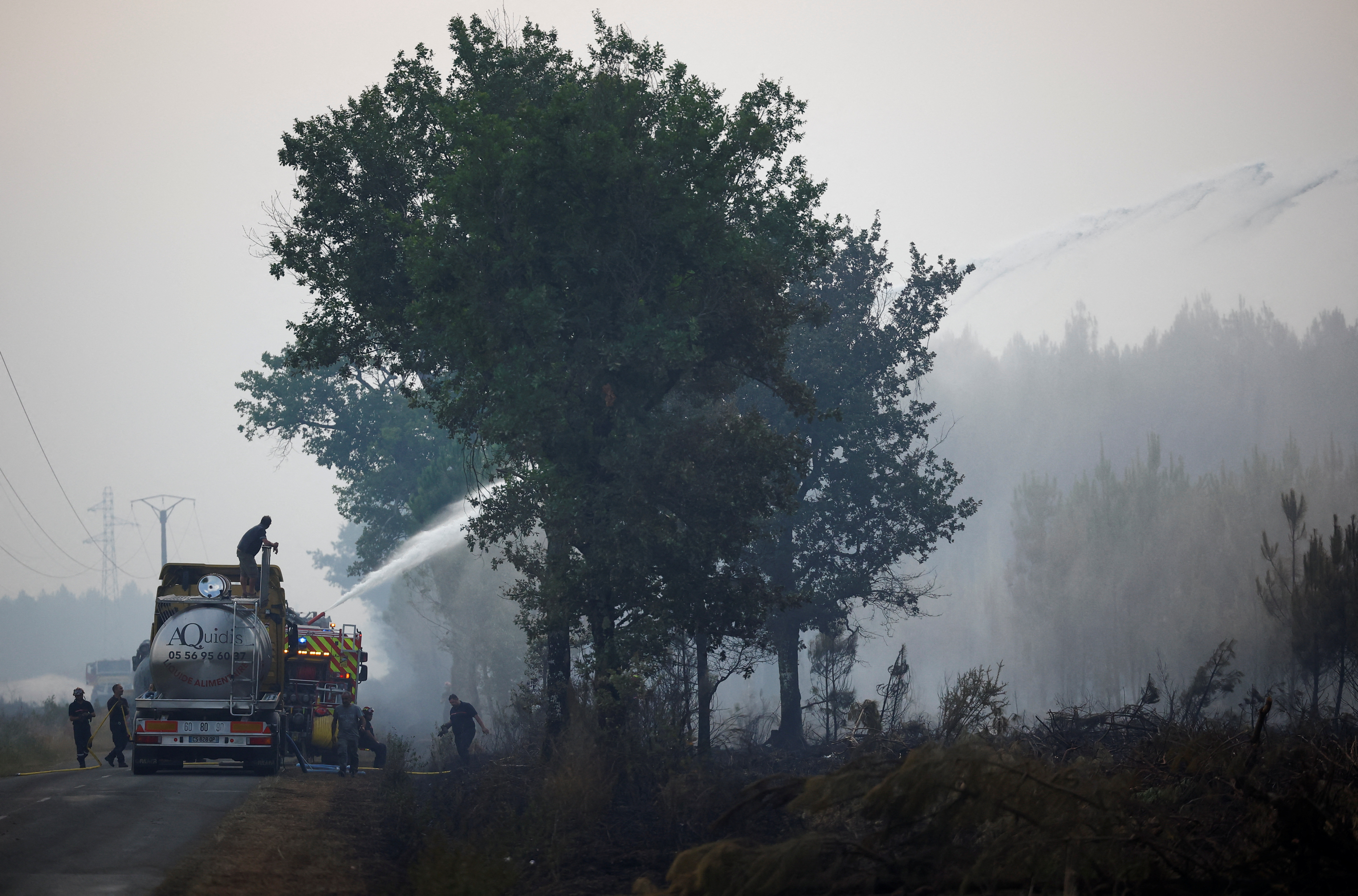 Farmers and firefighters work to contain a fire in Saint-Magne, as wildfires continue to spread in the Gironde region of southwestern France