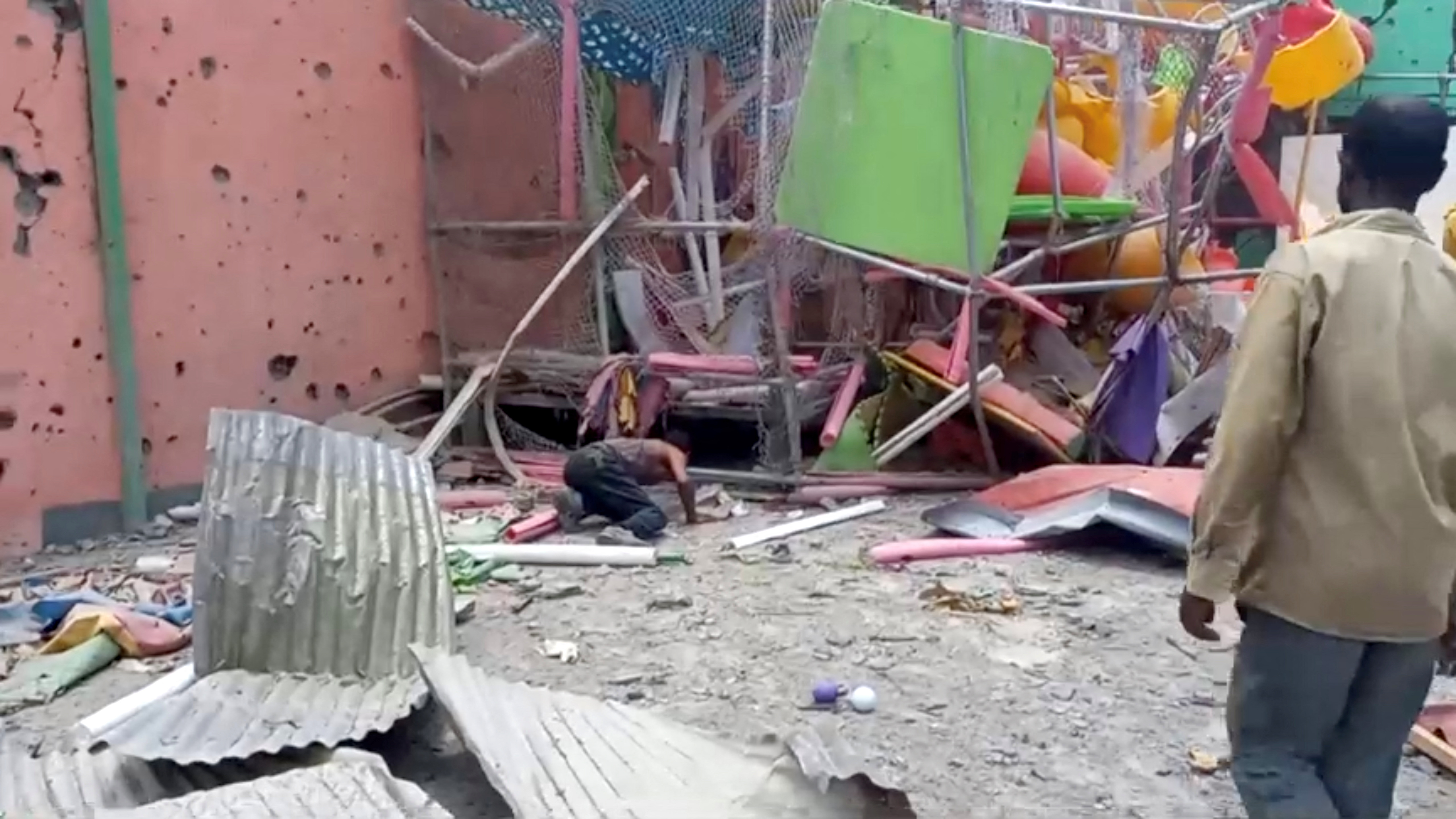 A man crouches to inspect a damaged playground following an air strike in Mekelle.