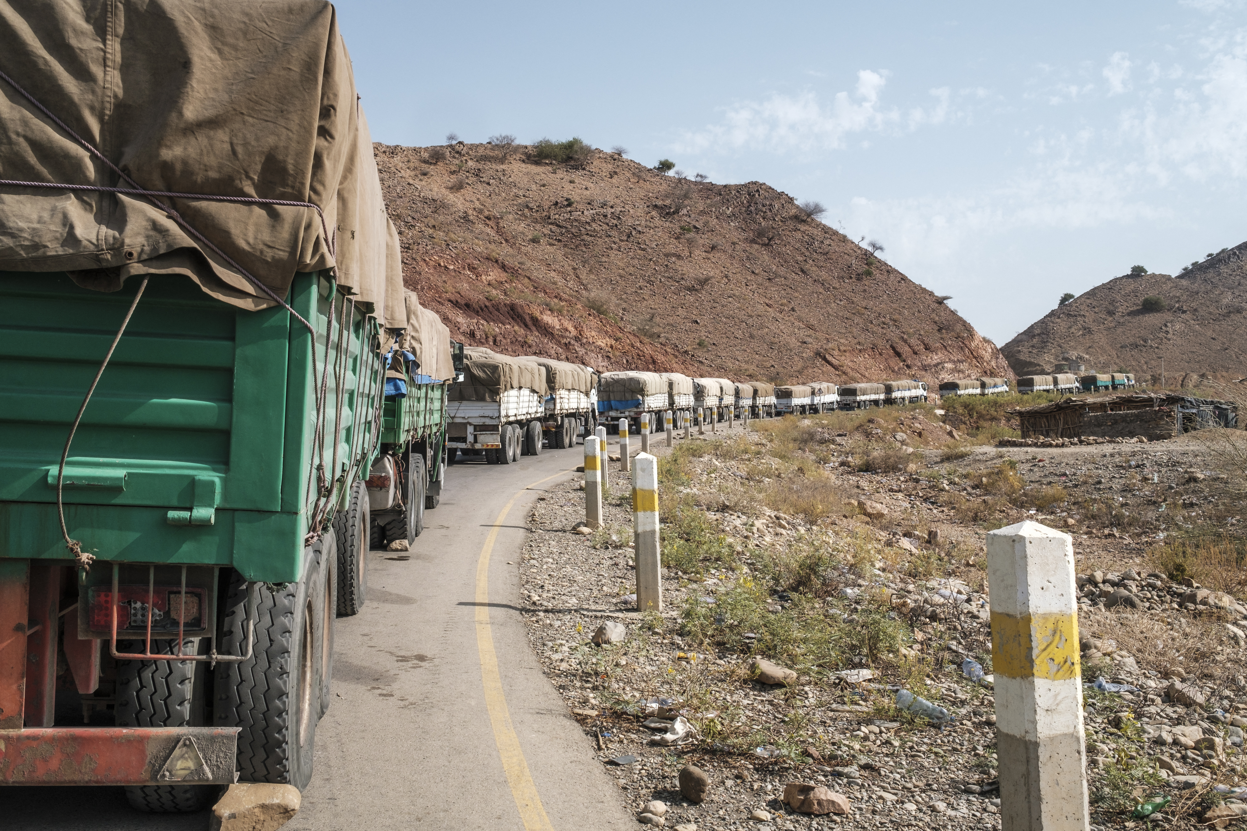 A convoy of trucks part of the World Food Programme (WFP) on their way to Tigray are seen in the village of Erebti, Ethiopia, on June 9, 2022. - The Afar region, the only passageway for humanitarian convoys bound for Tigray, is itself facing a serious food crisis, due to the combined effects of the conflict in northern Ethiopia and the drought in the Horn of Africa which have notably caused numerous population displacements. More than a million people need food aid in the region according to the World Food Programme. (Photo by EDUARDO SOTERAS / AFP)
