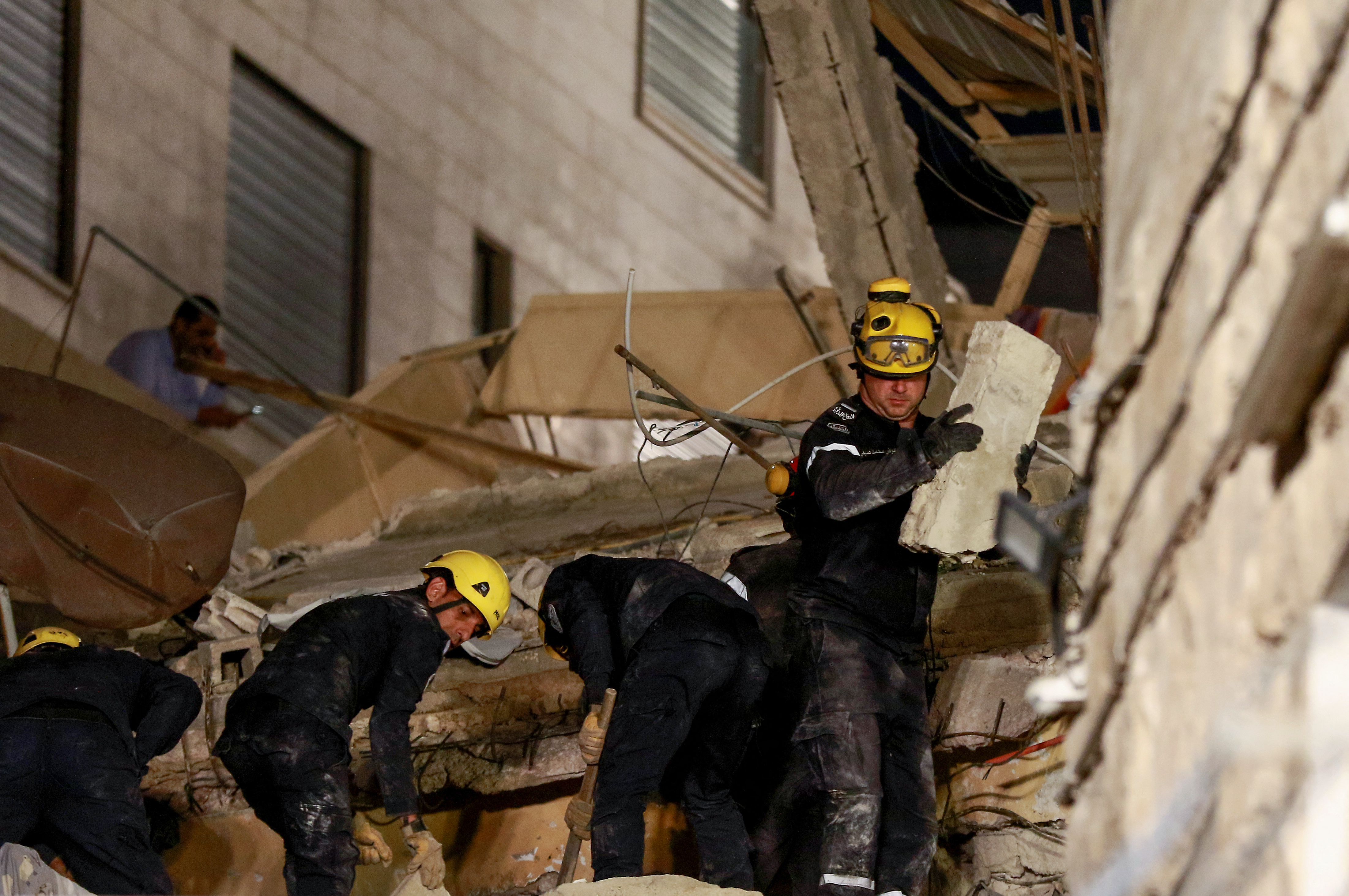 Jordanian rescue workers search for missing persons under the rubble of a four-storey residential building that collapsed in central Amman, on September 13, 2022