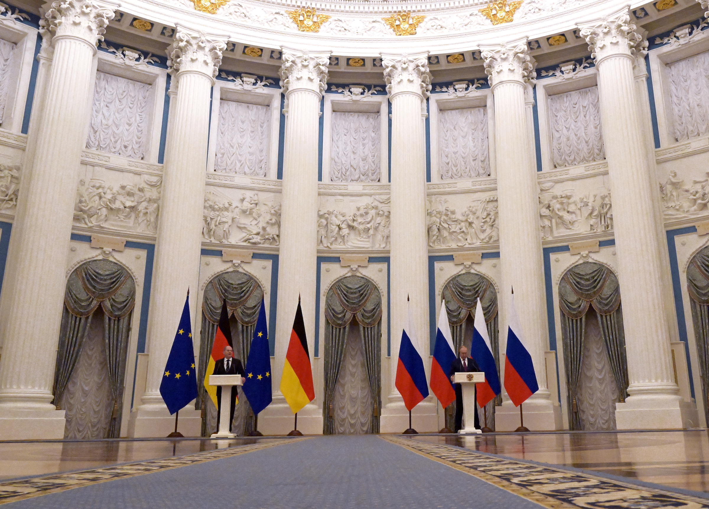 German Chancellor Olaf Scholz and Russian President Vladimir Putin speaking from lecterns during a press conference..