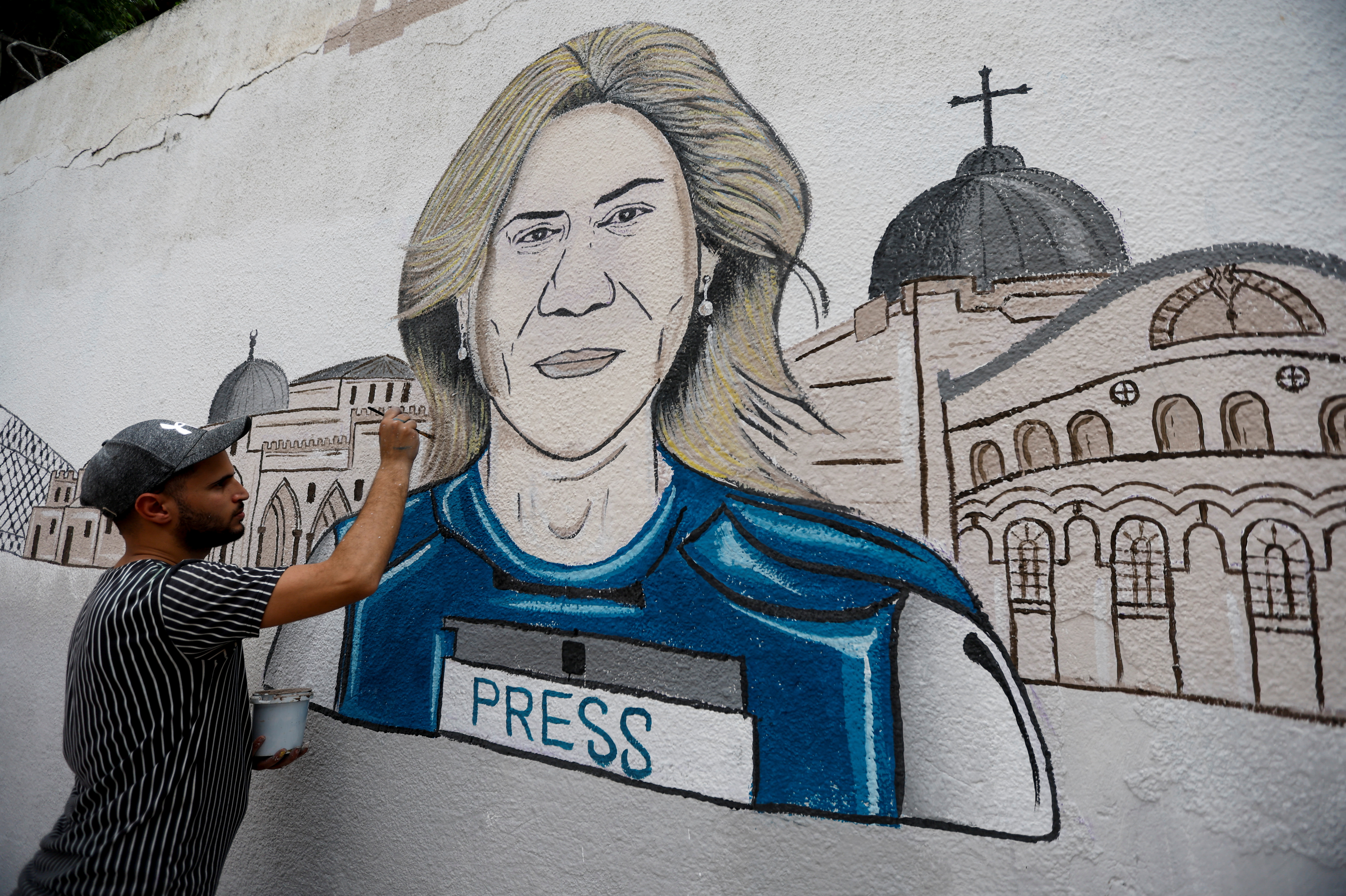 A man participates in drawing a mural of Al Jazeera reporter Shireen Abu Akleh, killed during an Israeli raid in the Israeli-occupied West Bank, in Khan Younis in the southern Gaza Strip May 14, 2022.