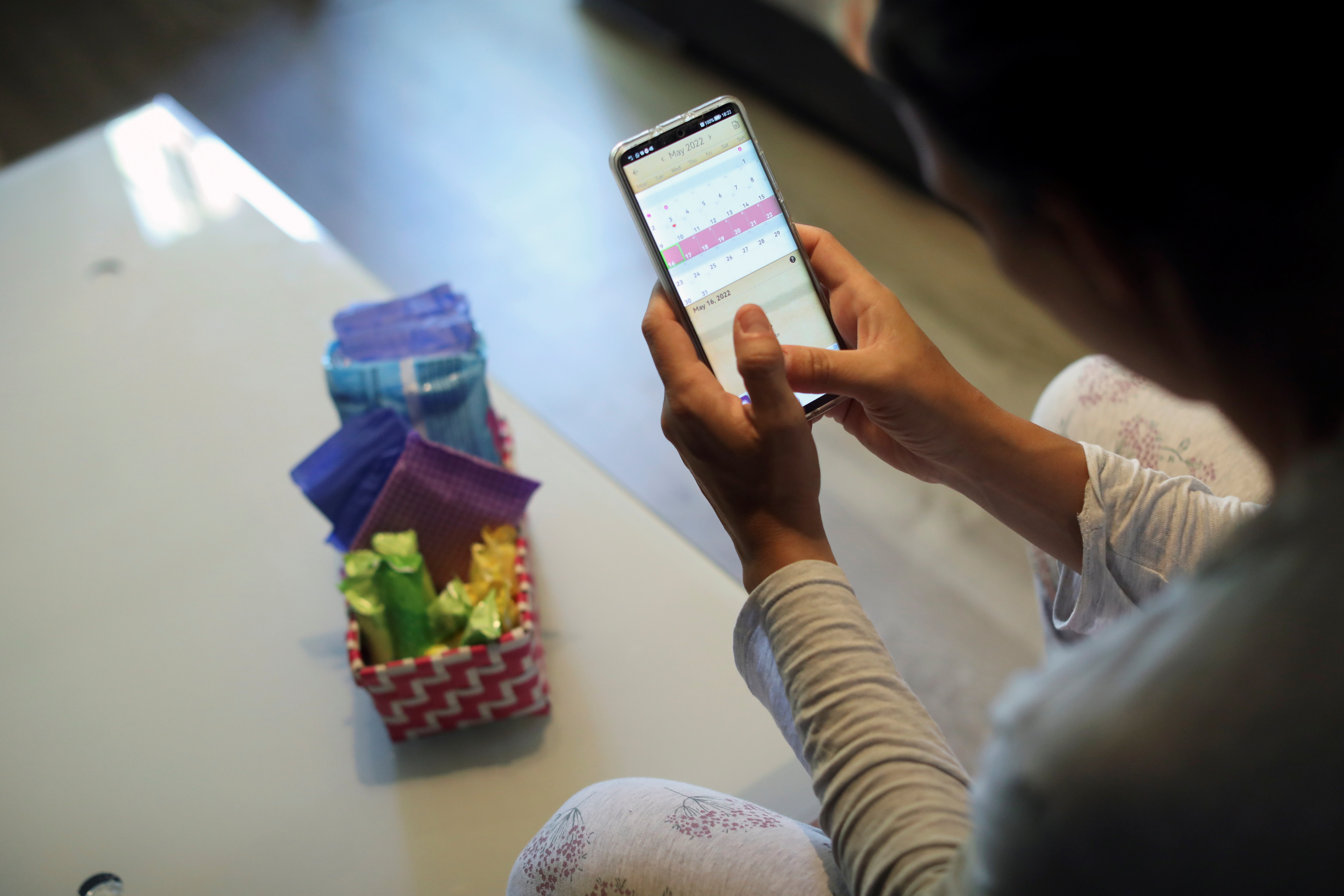Raquel del Rio, 36, who works in police forces, poses as she observes a period calendar tracker app on her mobile phone at her home in Madrid, Spain, May 16, 2022