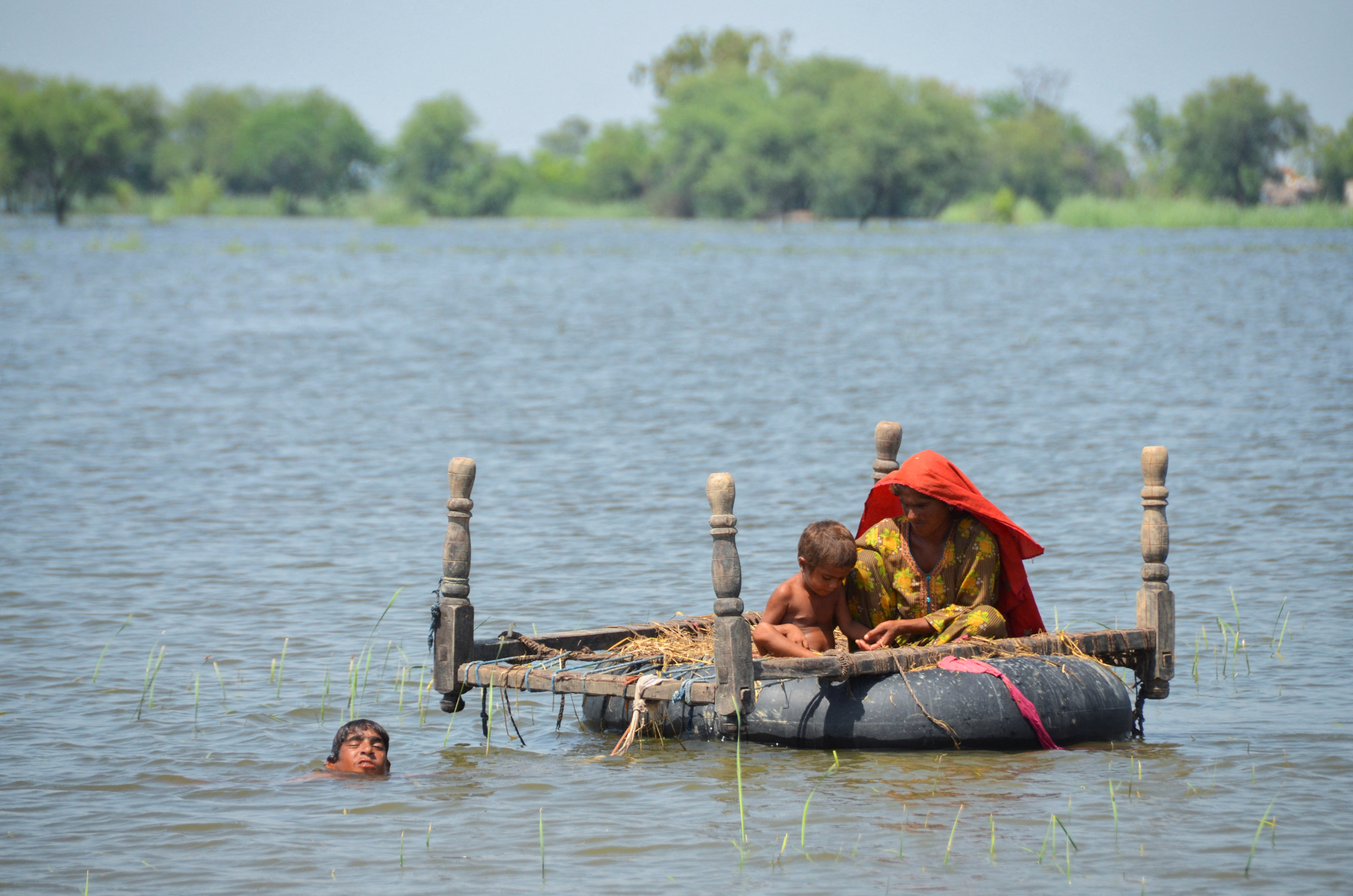 Flood victims use an inflatable tube as they travel in flood waters, following rains and floods during the monsoon season, in Dera Allah Yar, Jafferabad, Pakistan August 31, 2022. REUTERS/Amer Hussain NO RESALE. NO ARCHIVE.
