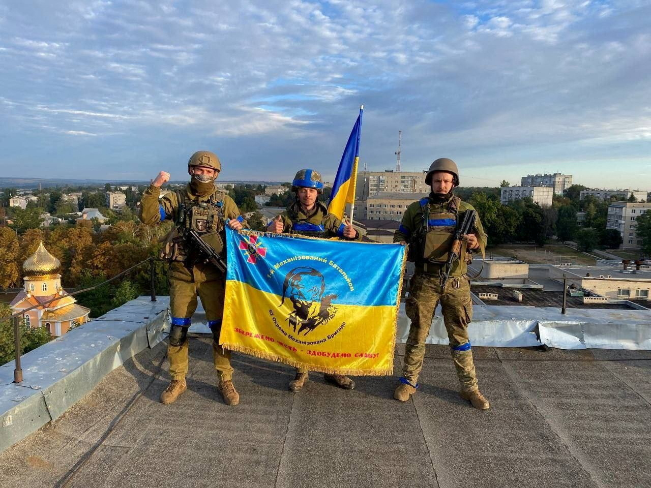 Ukrainian soldiers hold a flag on a rooftop in Kupiansk, Ukraine in this picture obtained from social media released on September 10, 2022