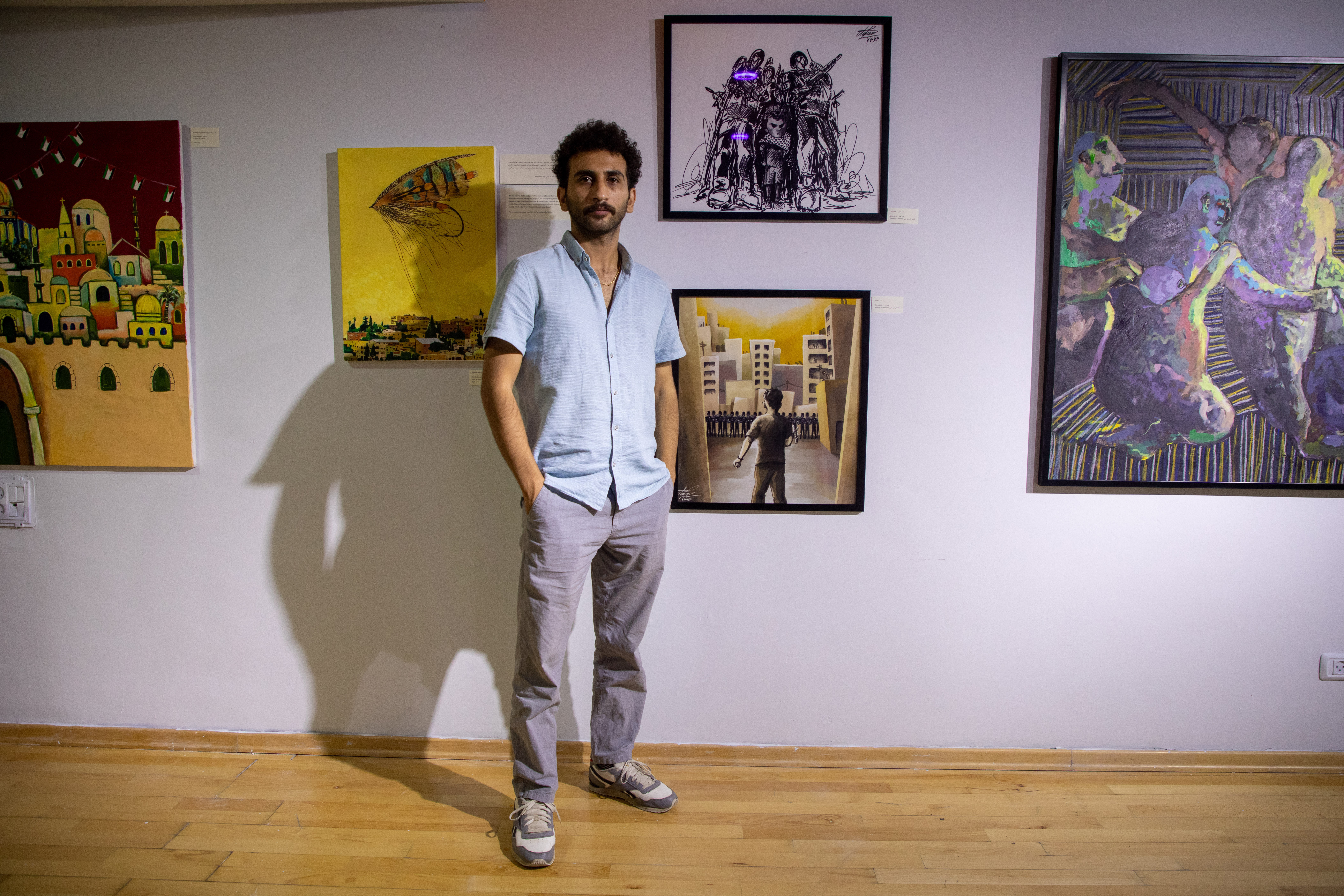 Azeez Azeez, 29, standing next to on the left of two pieces of his art at the Yabous festival in occupied East Jerusalem