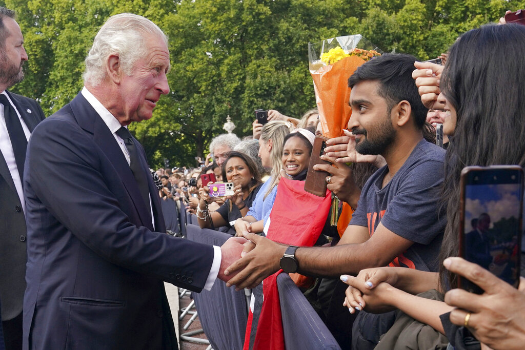 King Charles III greets well-wishers as he walks by the gates of Buckingham Palace following Thursday’s death of Queen Elizabeth II, in London