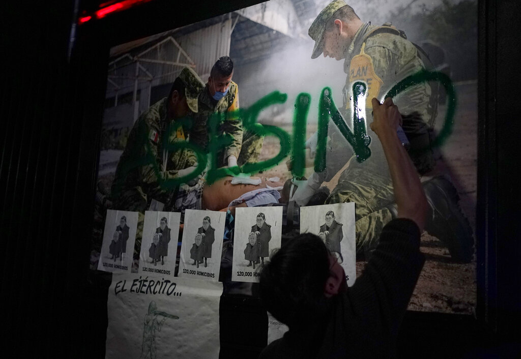 A protestor spray paints a picture of a member of the military