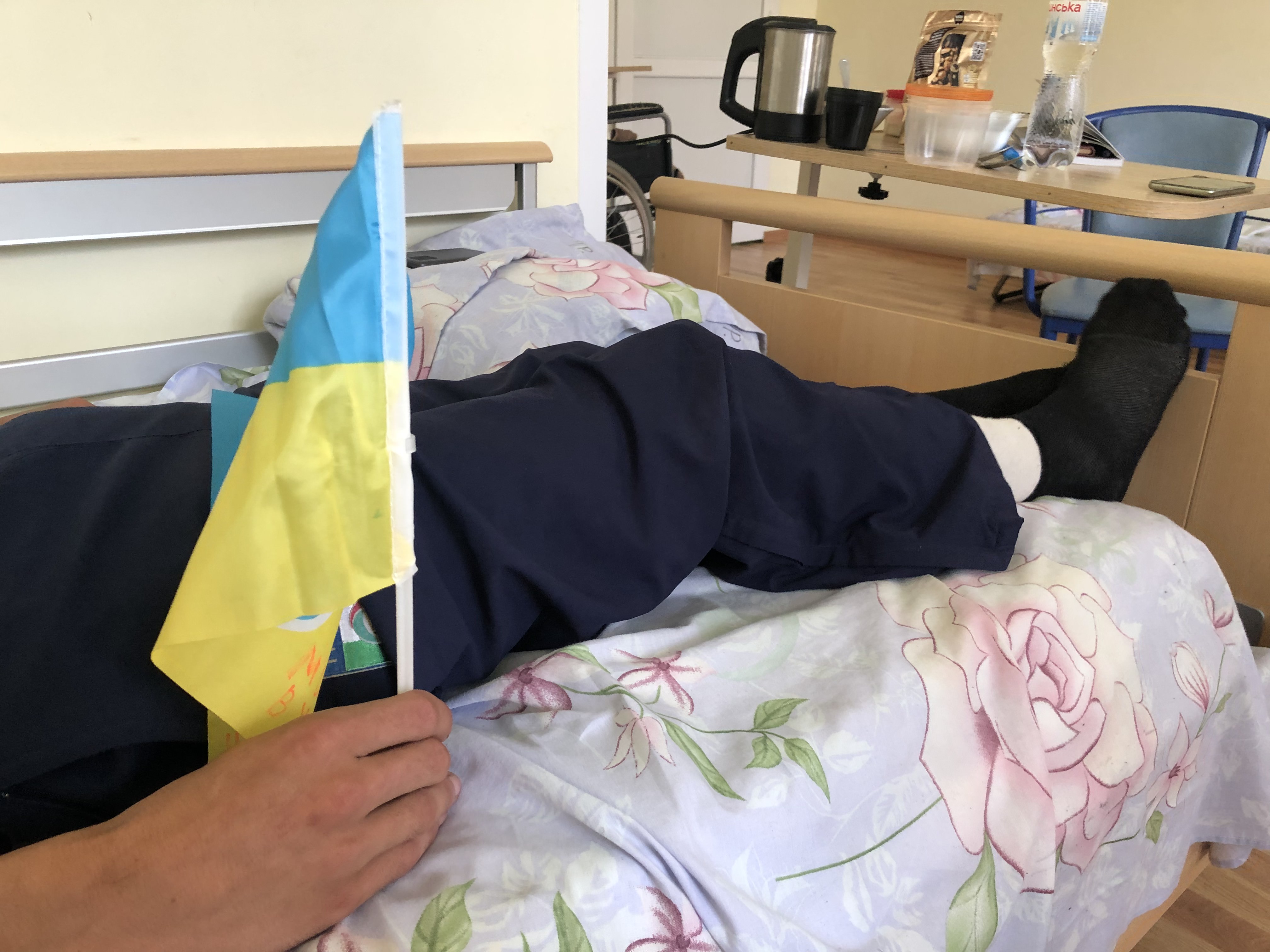 Yehor holds a Ukrainian flag. He wants to go home and meet with the members of his unit who survived. ‘They’re like my family,’ he says