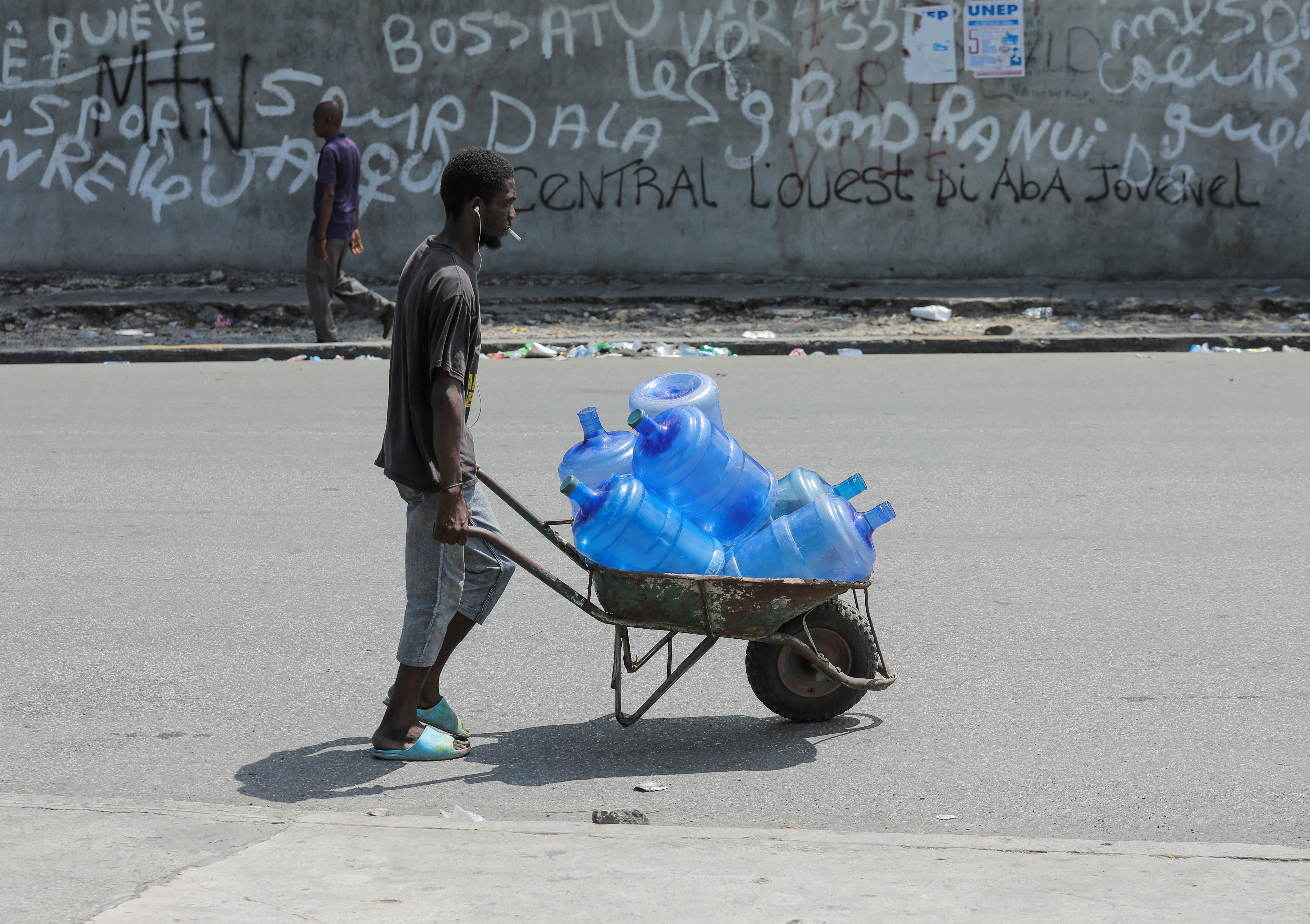 A man pushes a barrel with empty water containers