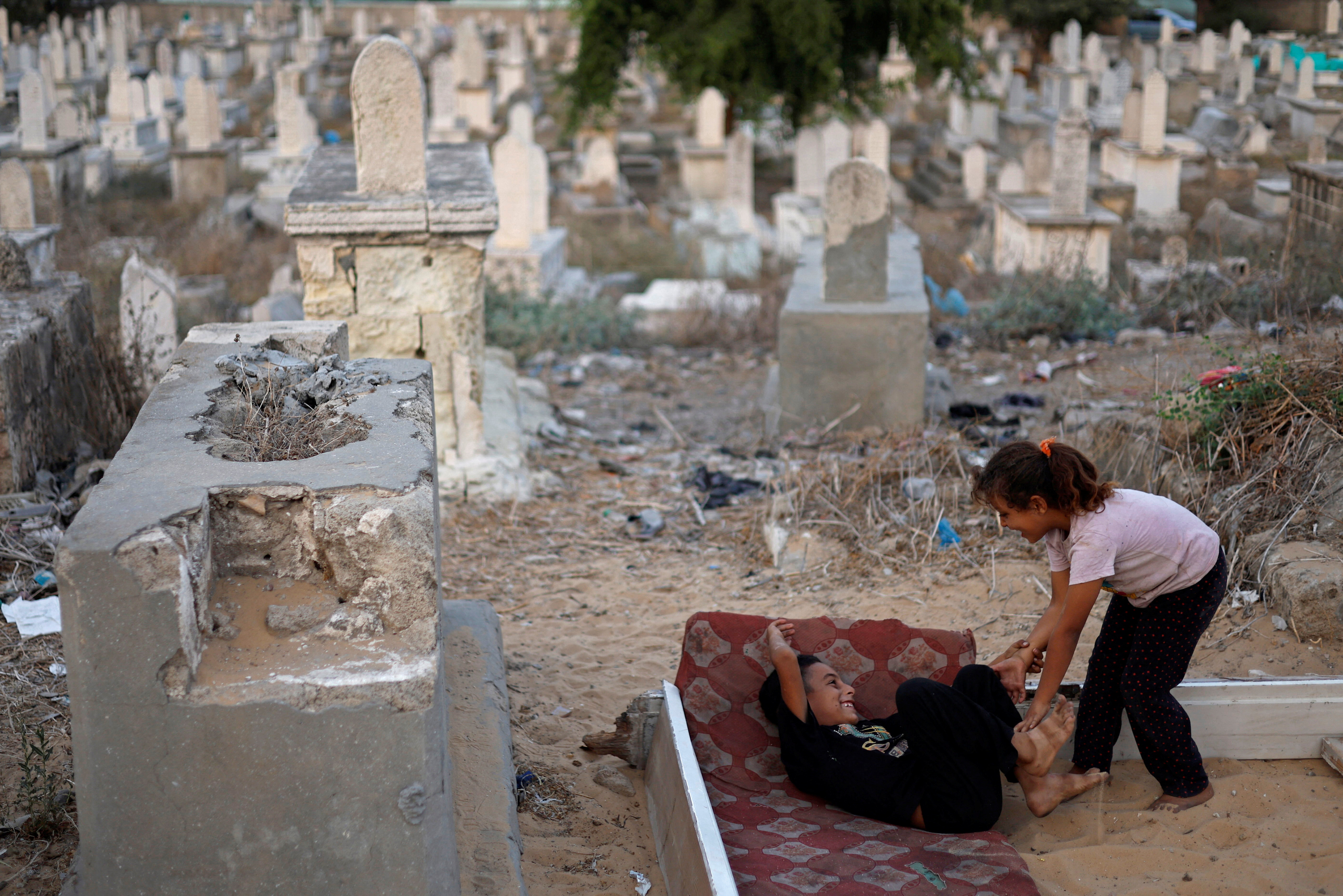Mohammad Kuhail and his twin sister Yosra play on graves in the Sheikh Shaban cemetery. The children, who earn small amounts bringing water to funeral ceremonies, keep asking their parents when they will be able to move away from the cemetery