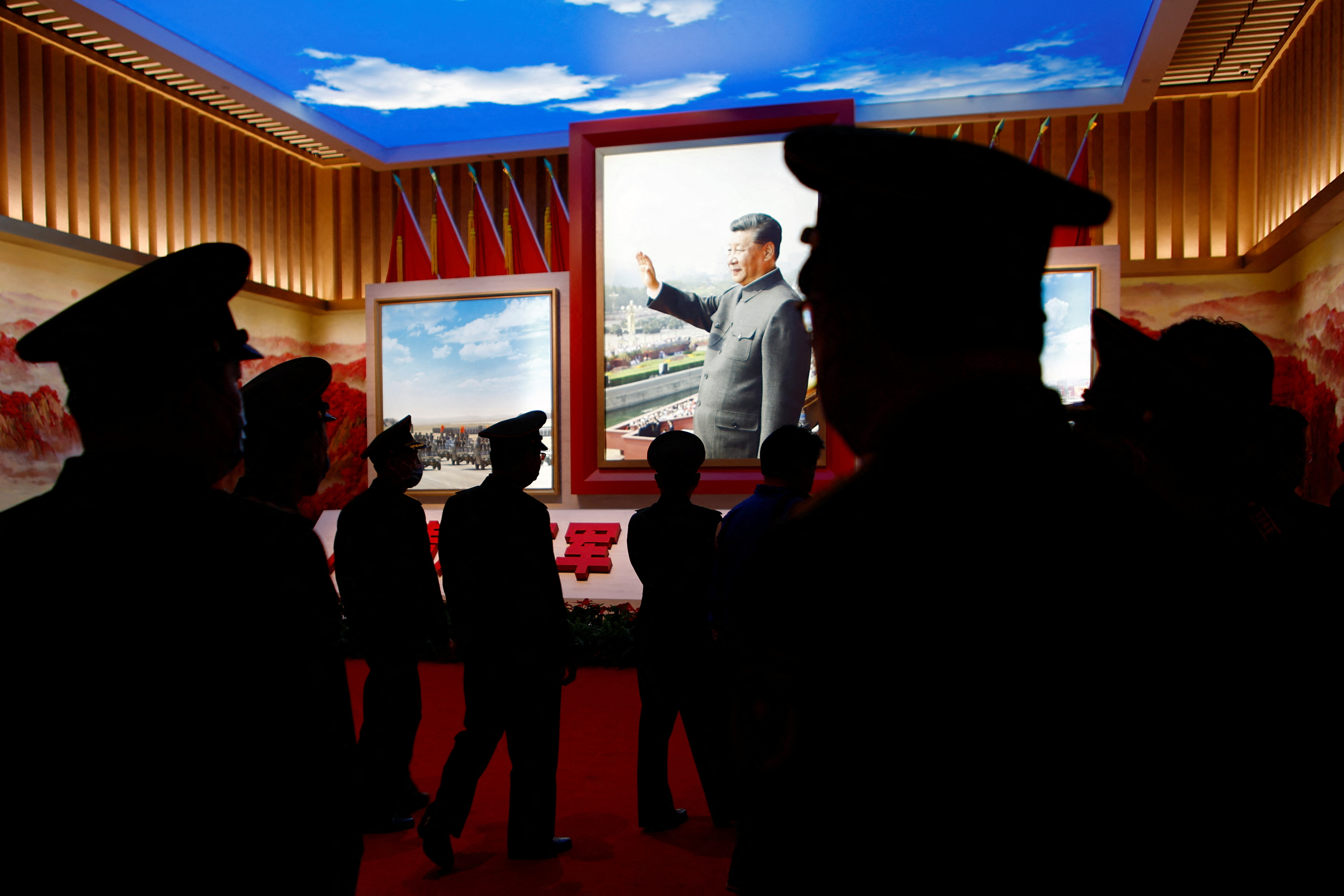 Members of the Chinese People’s Liberation Army (PLA) walk past an image of Chinese President Xi Jinping at an exhibition at the Military Museum of the Chinese People’s Revolution in Beijing