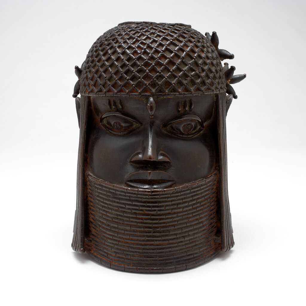 The "Head of a King", a dark, bronze sculpture, shows the king wearing a cap of coral beads with a single cowrie shell placed on the middle of his forehead