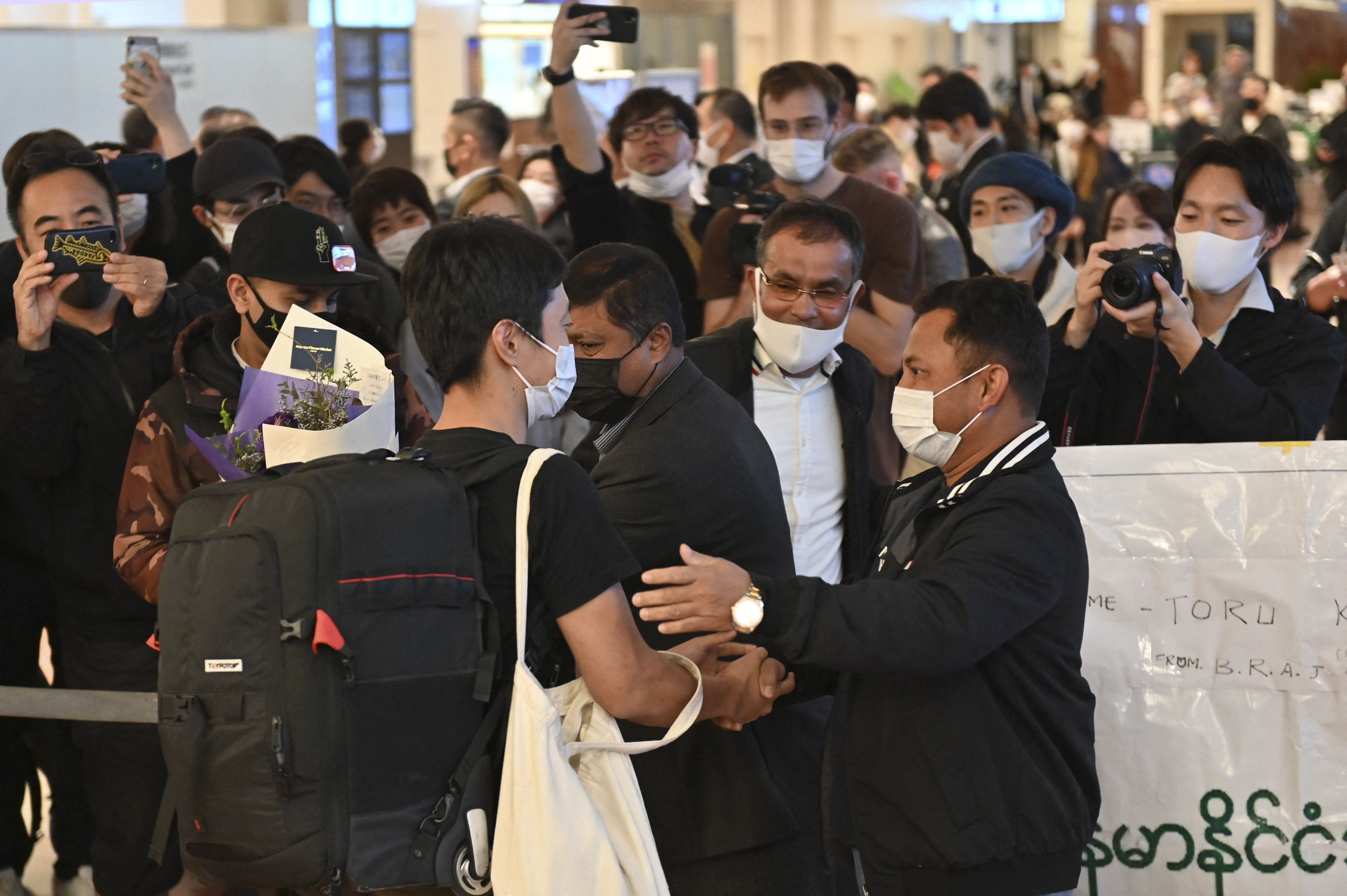 Japanese journalist Toru Kubota (front left) welcomed by his supporters on his arrival at Tokyo’s Haneda Airport after being released from a Myanmar prison, in Tokyo on November 18, 2022