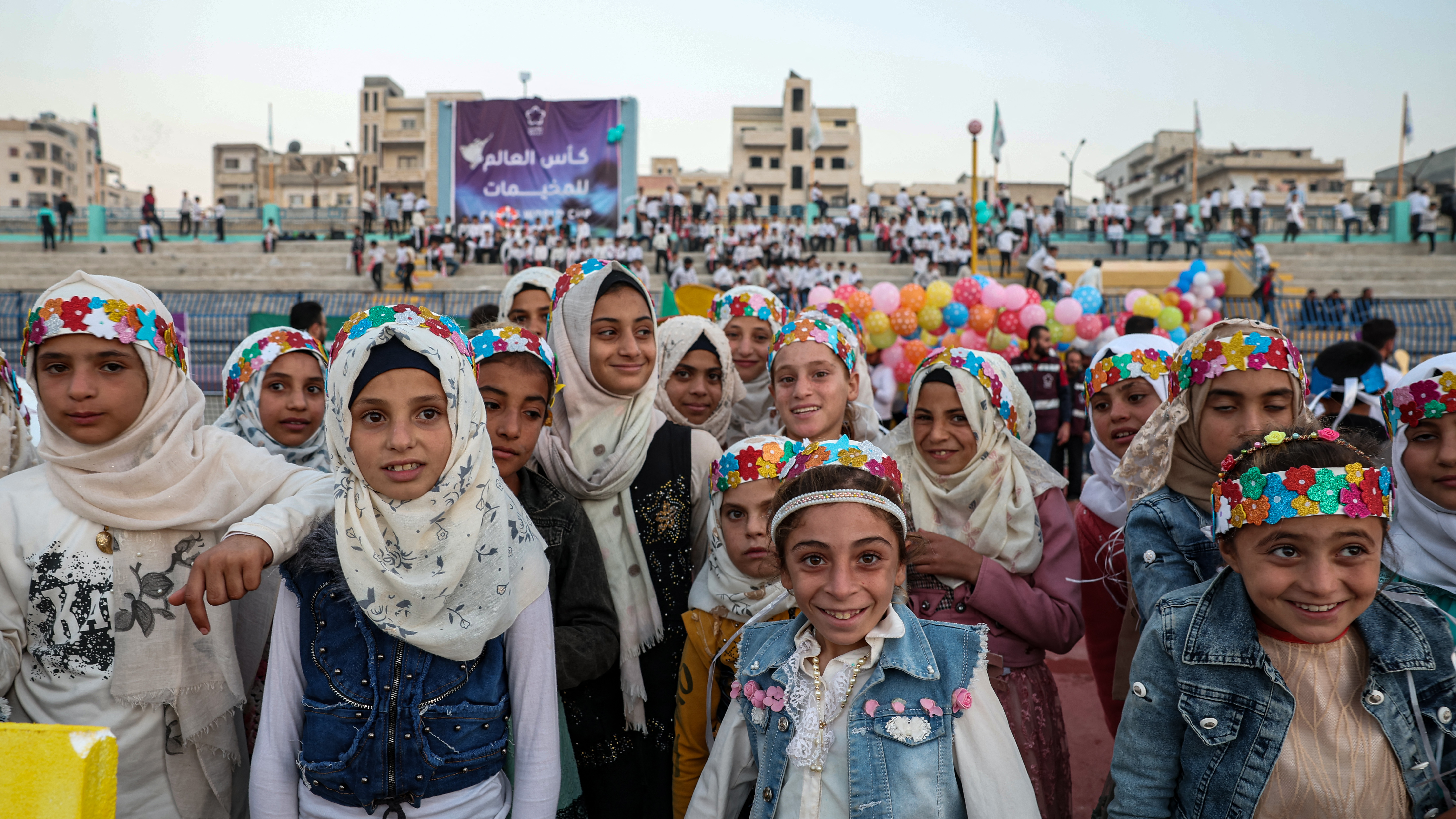 Girls line up and pose together on the pitch during the opening ceremony of the ‘Camps World Cup’ at the newly reopened Idlib Municipal Stadium in the rebel-held northwestern Syrian city
