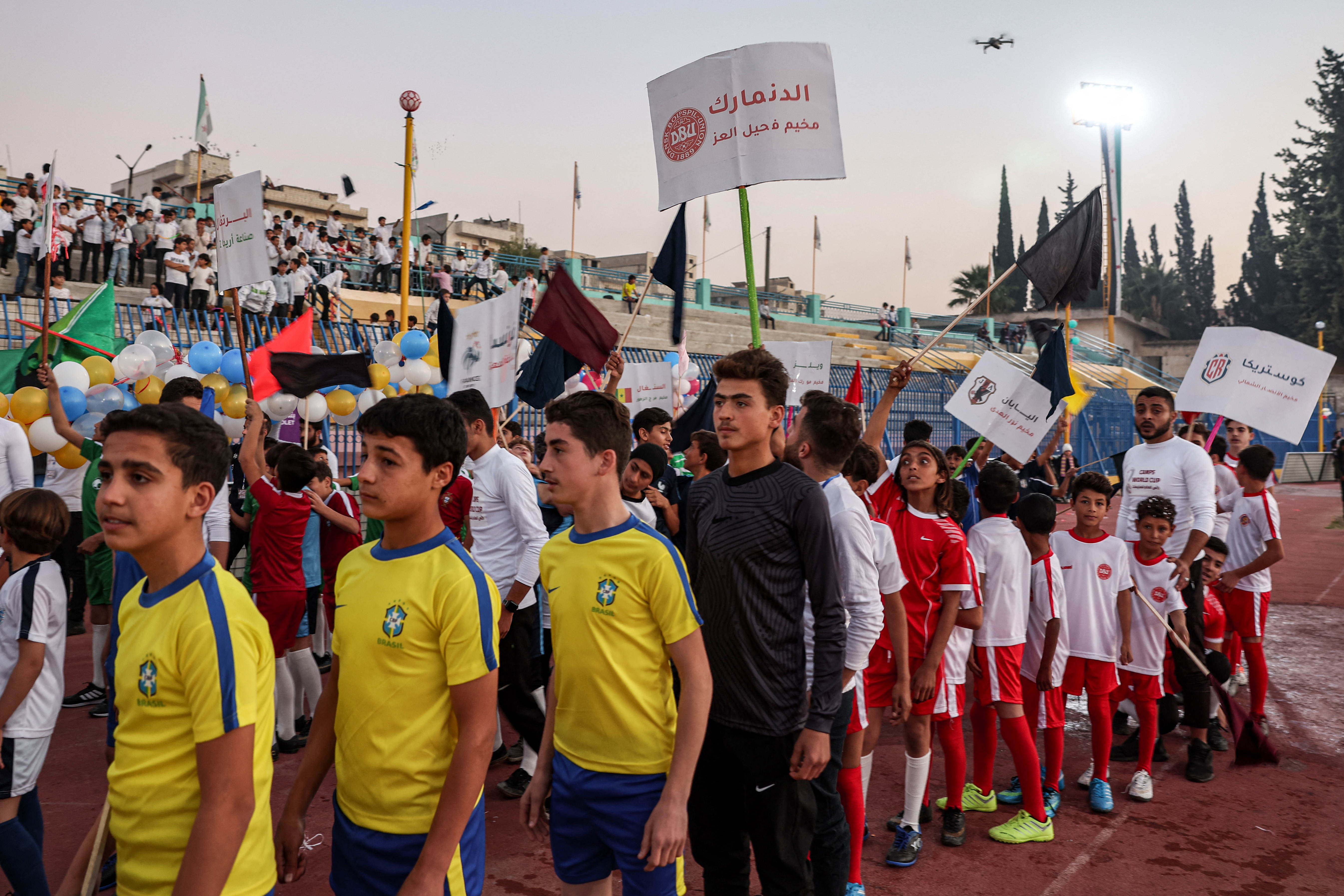 Children wearing the uniforms of national football teams playing at the Qatar 2022 FIFA World Cup line up during the opening ceremony of the ‘Camps World Cup’