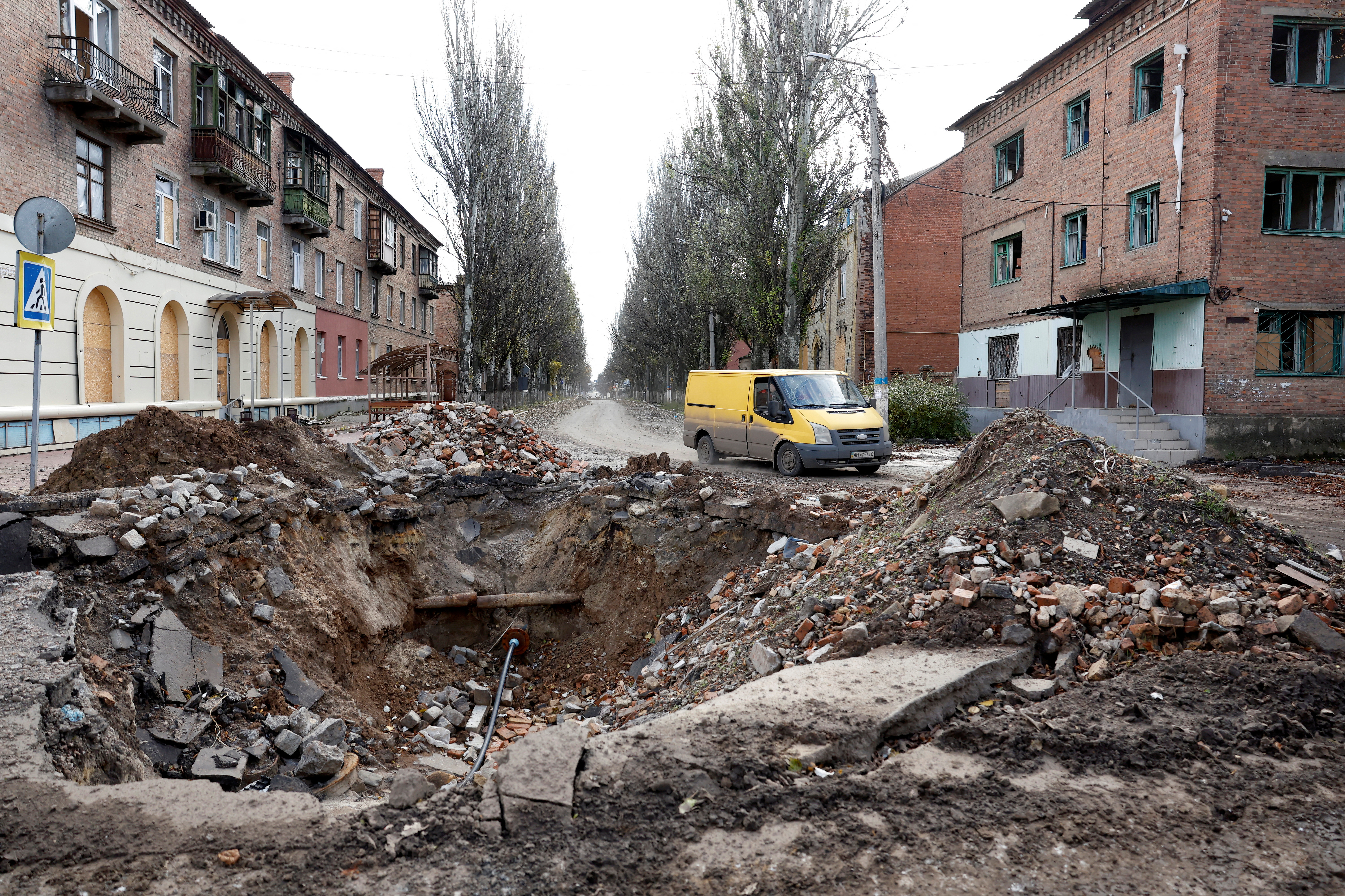 A van drives past a crater in the road caused by a missile raid, as Russia’s invasion of Ukraine continues, in the eastern Donbas region of Bakhmut