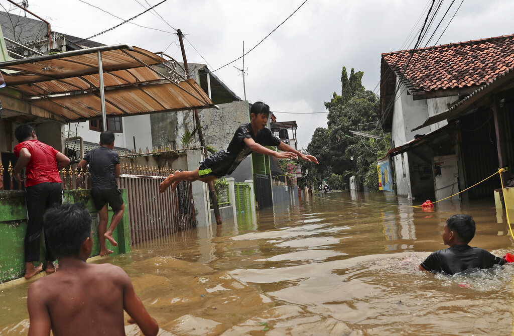 Indonesian youths play in flood water in a neighbourhood in Jakarta after overnight rains caused rivers to burst their banks, inundating thousands of homes and paralysing parts of the city’s transport networks