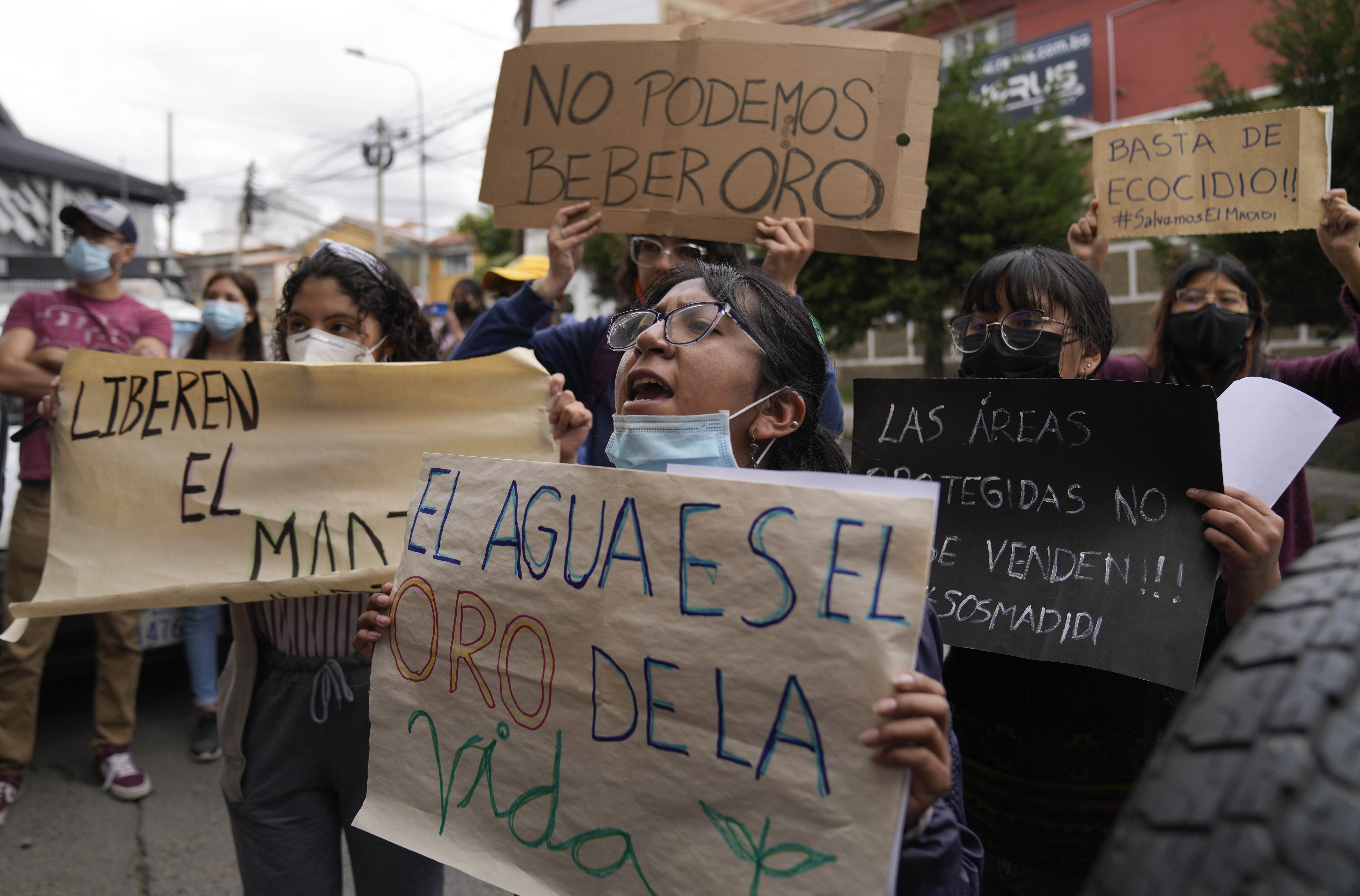 Activists in Bolivia hold hand-written signs protesting gold mining in Madidi National Park